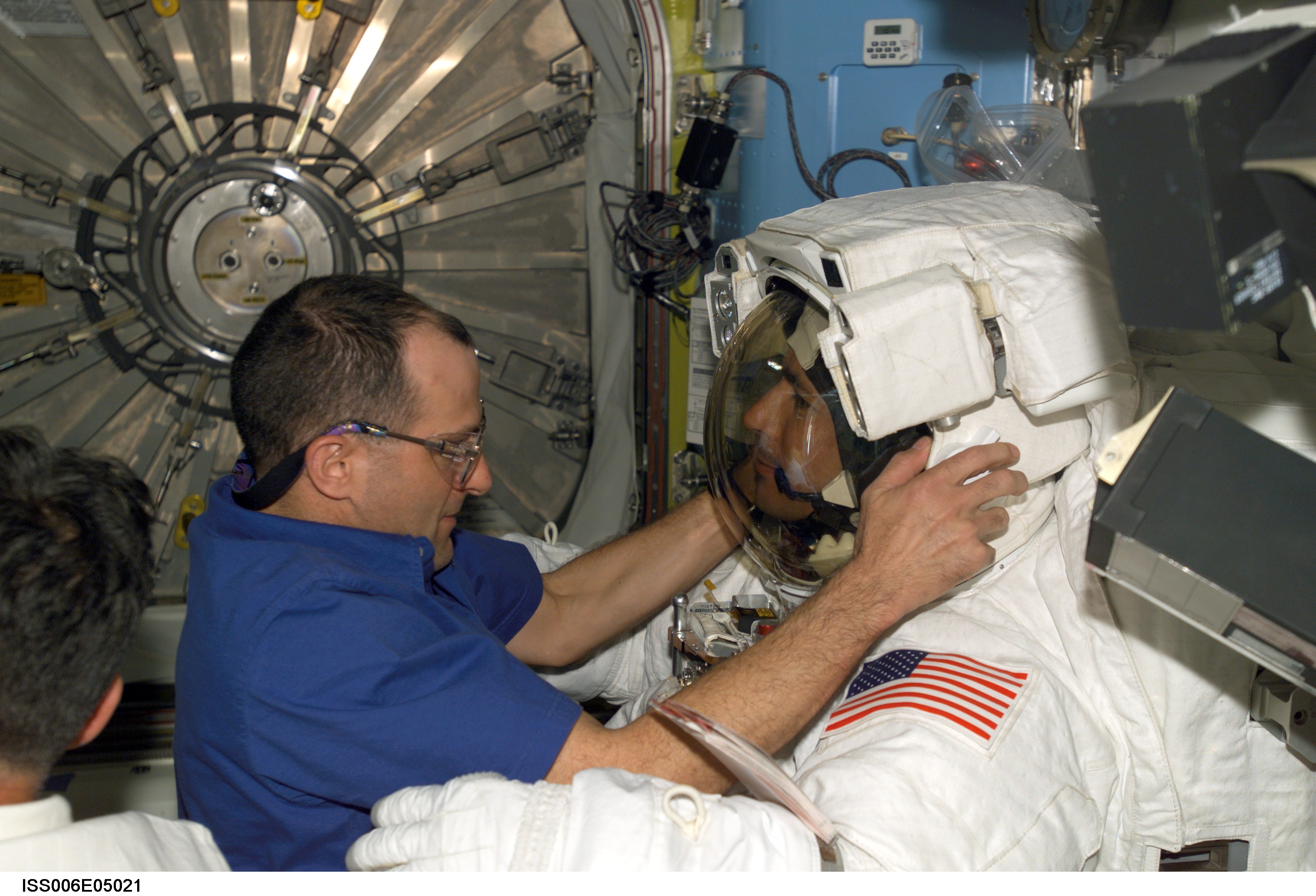 Expedition Six Flight Engineer Pettit is adjusting the helmet on STS-113 MS Herringtons EMU
