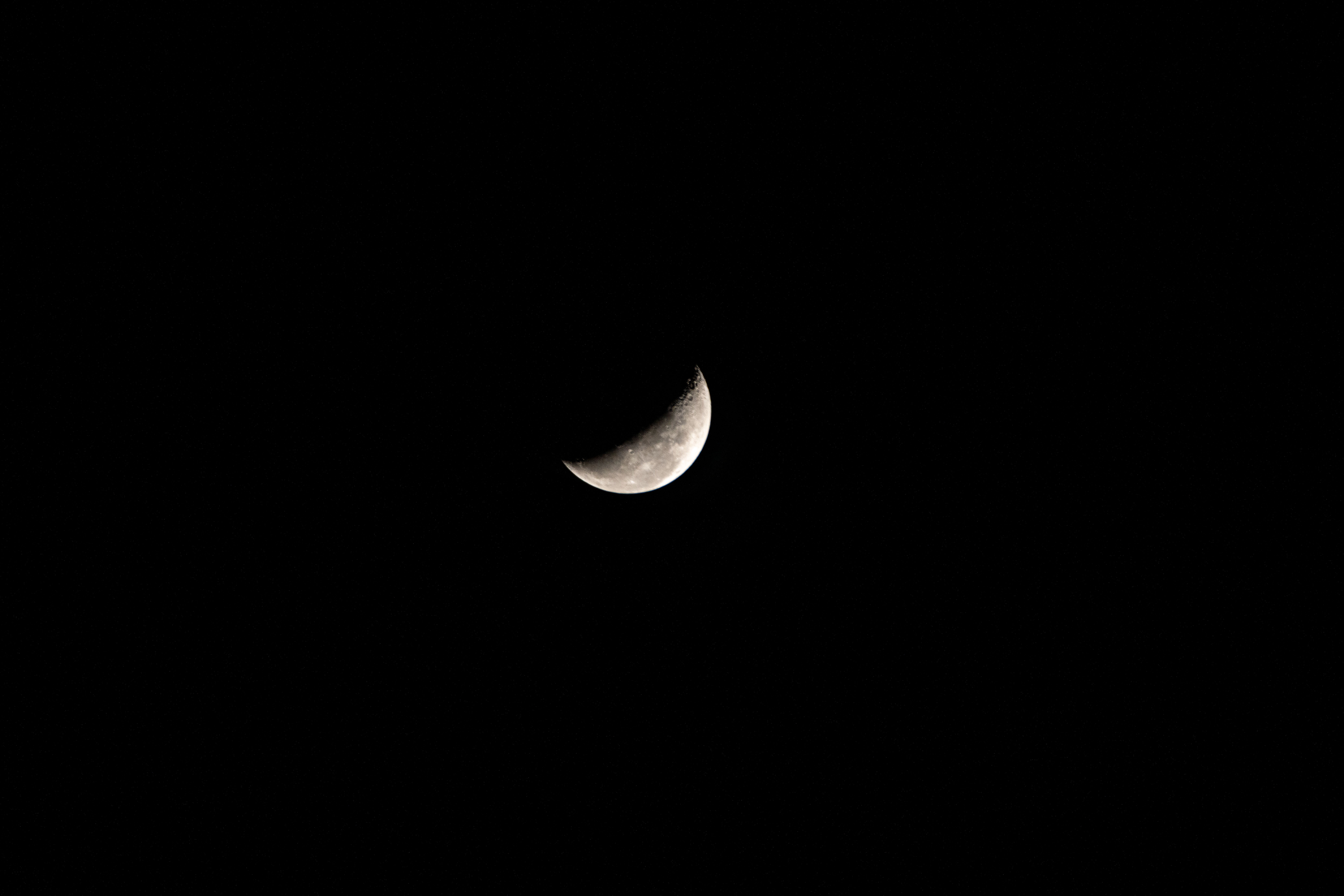 A waning crescent moon hangs against the black of space