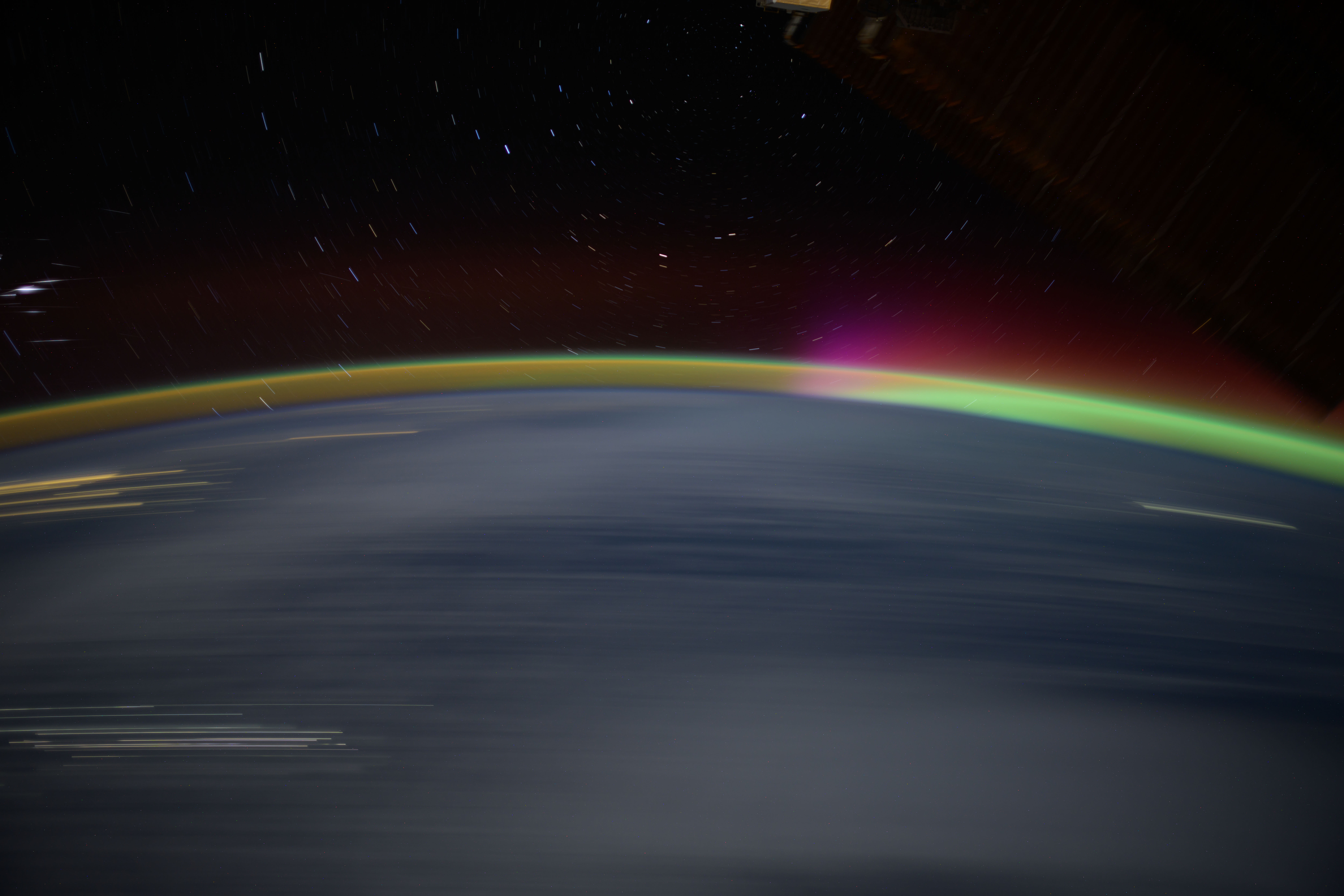 Streaks of city lights, star trails, an aurora, and Earth's atmospheric glow