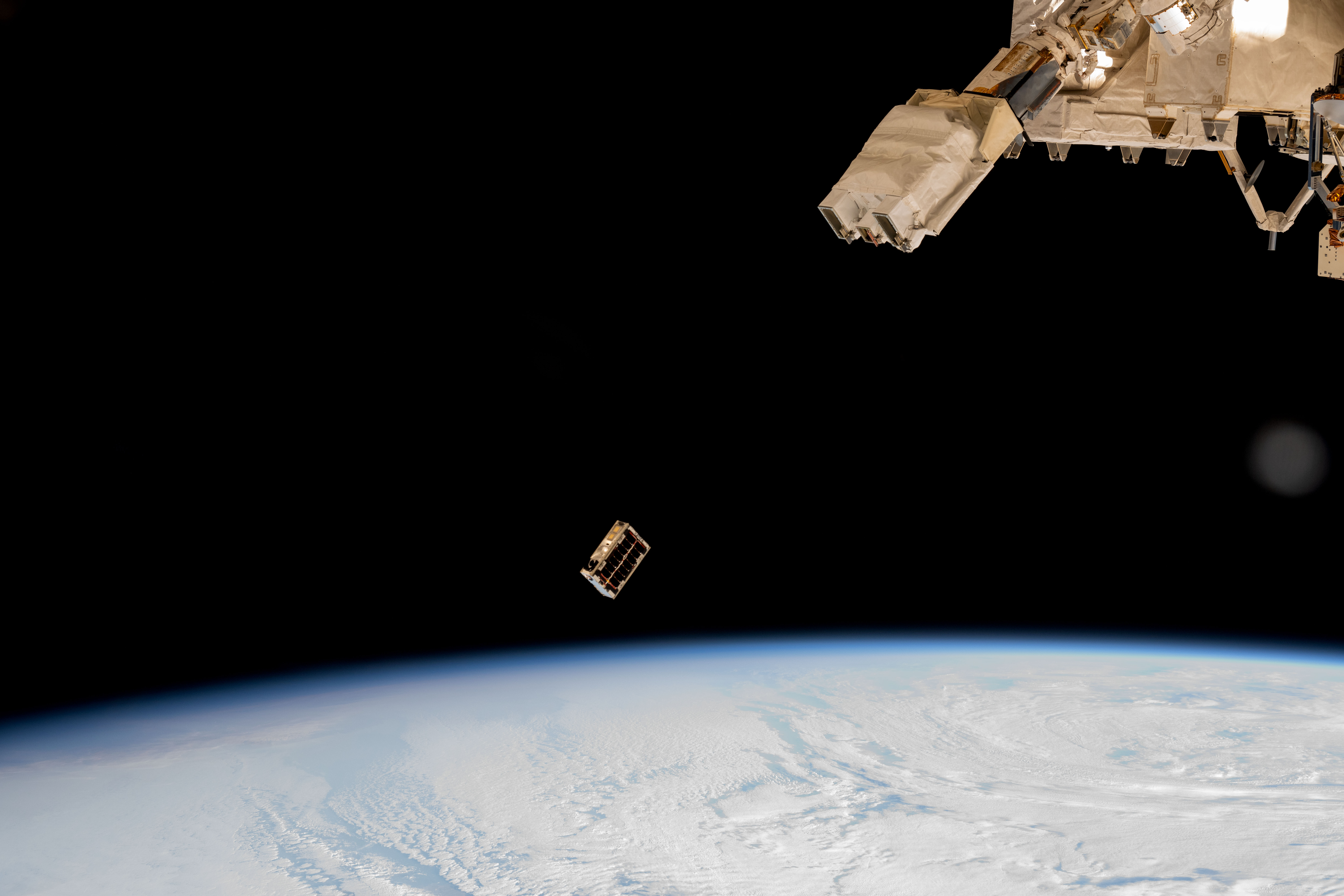 A CubeSat is ejected into Earth orbit from a small satellite orbital deployer
