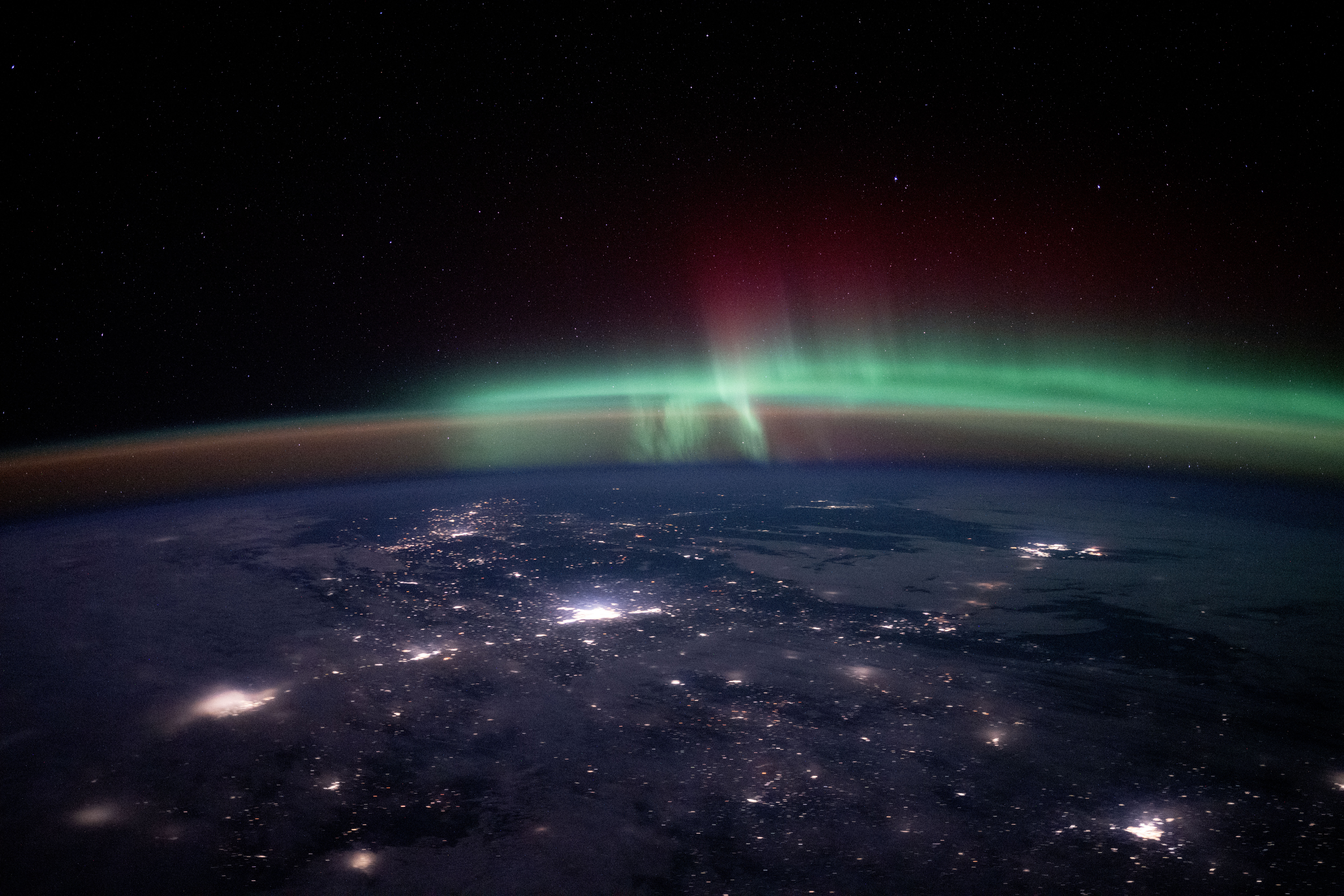 City lights dot the Canadian landscape underneath an aurora