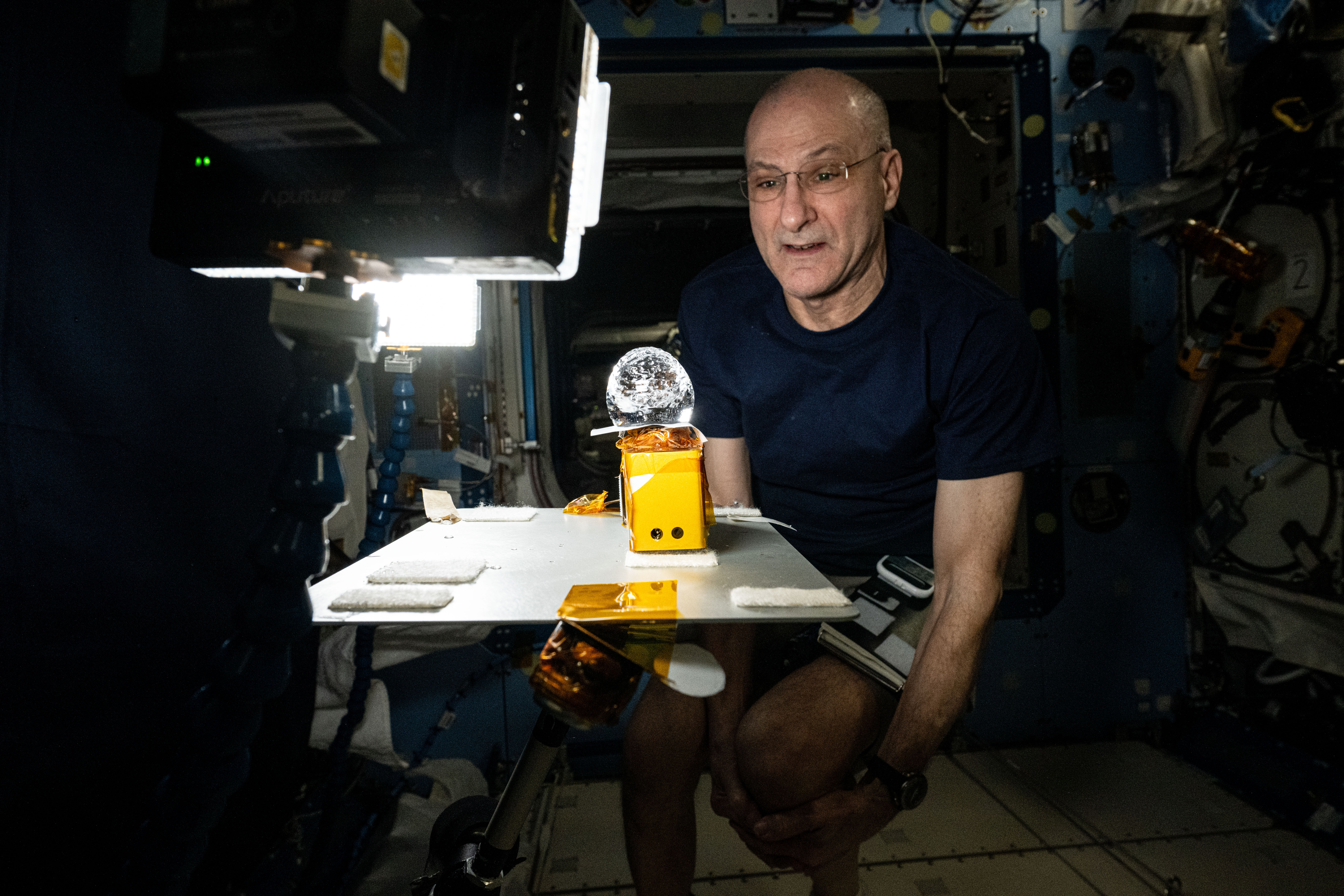 Astronaut Don Pettit stares at a ball of water shaped by microgravity