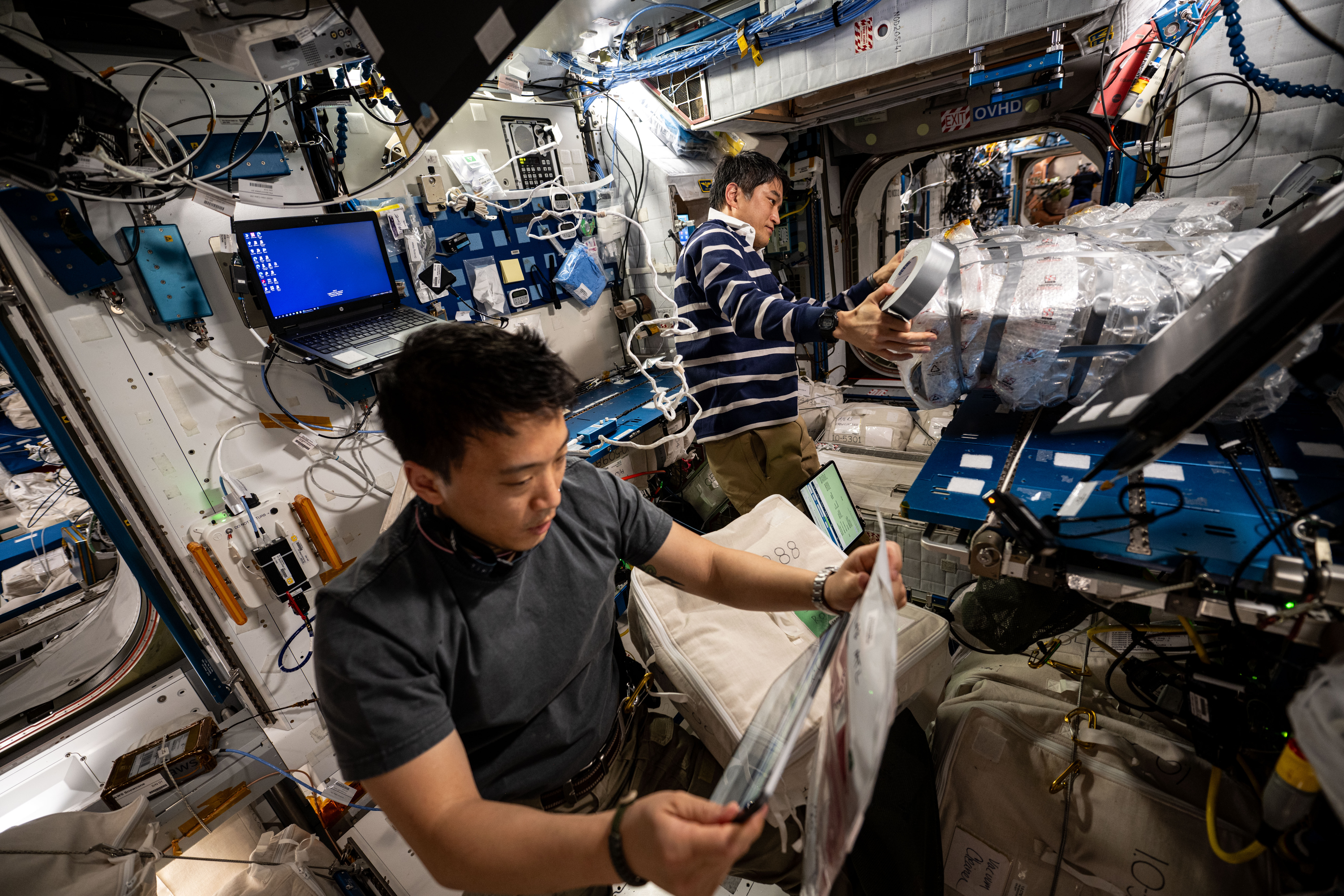 Astronauts Jonny Kim and Takuya gathers cargo to be packed inside the SpaceX Dragon cargo spacecraft
