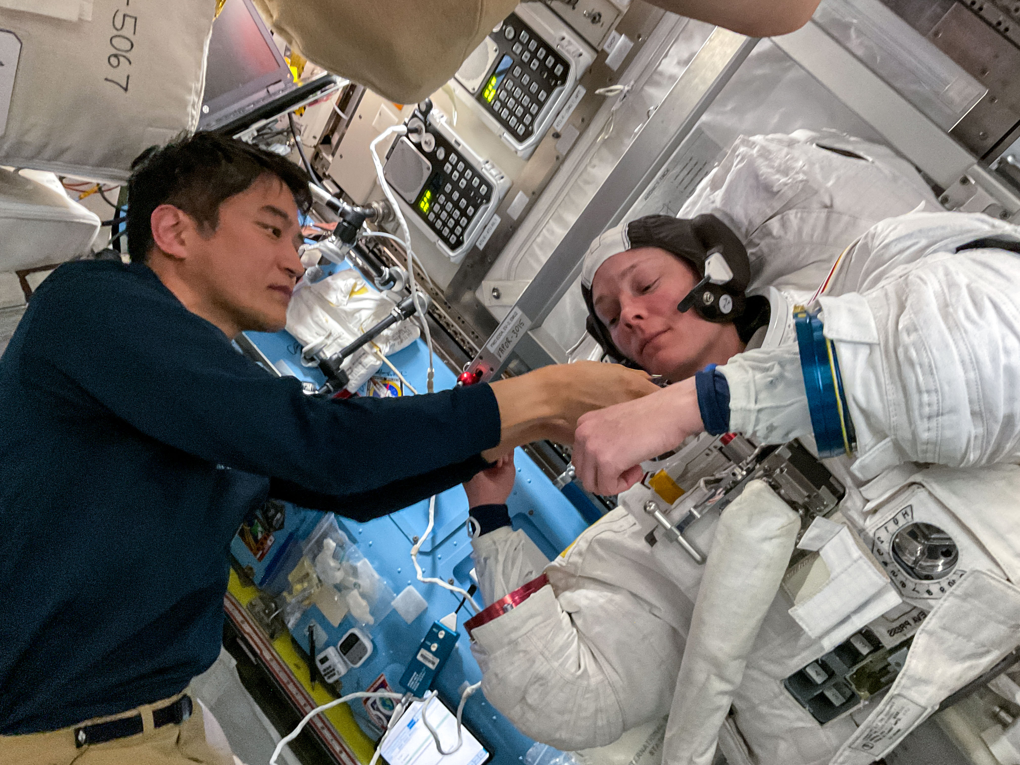 Astronaut Takuya Onishi assists Nichole Ayers as she tries on a spacesuit