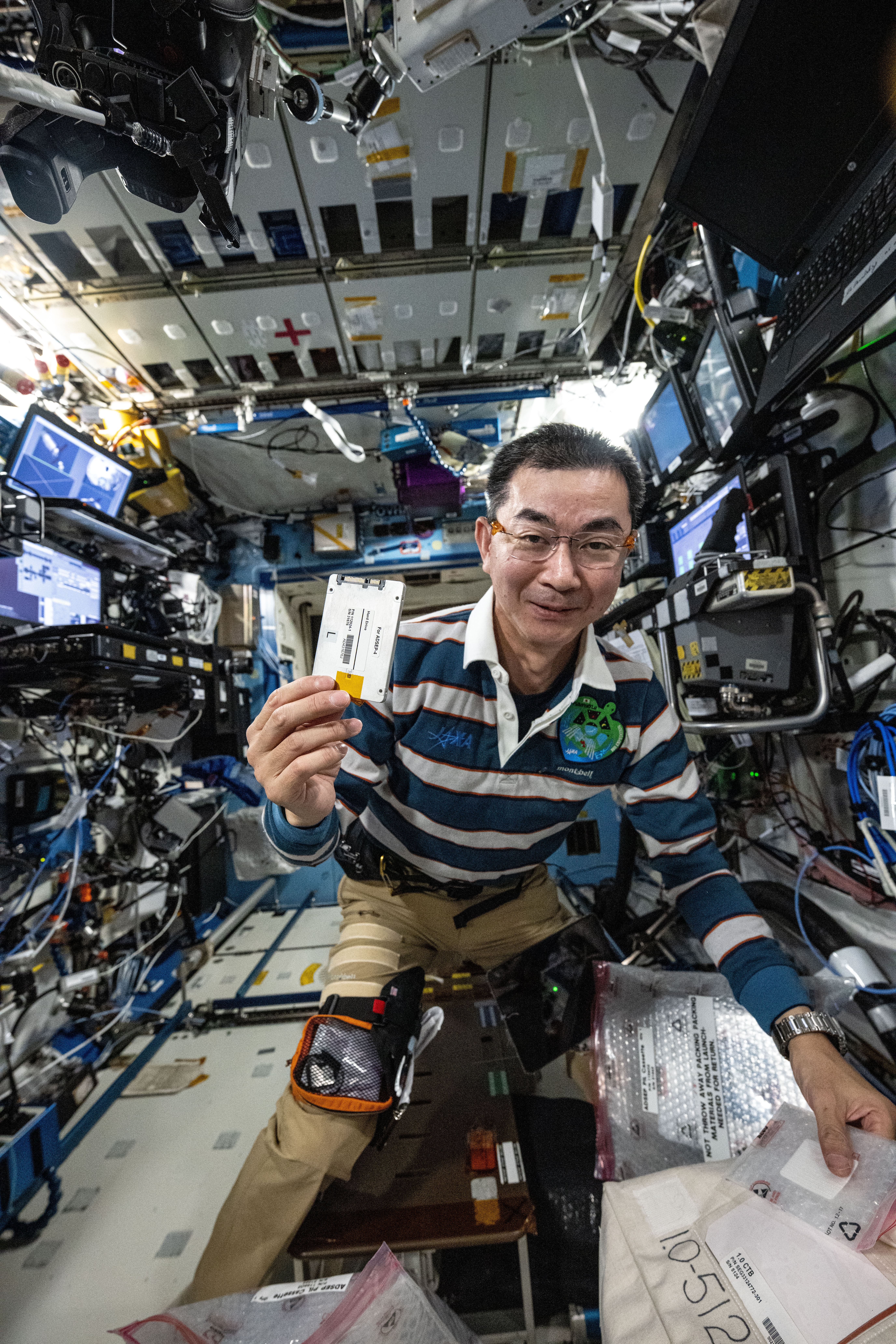 JAXA astronaut Kimiya Yui shows off a research hard drive for an pharmaceutical investigation