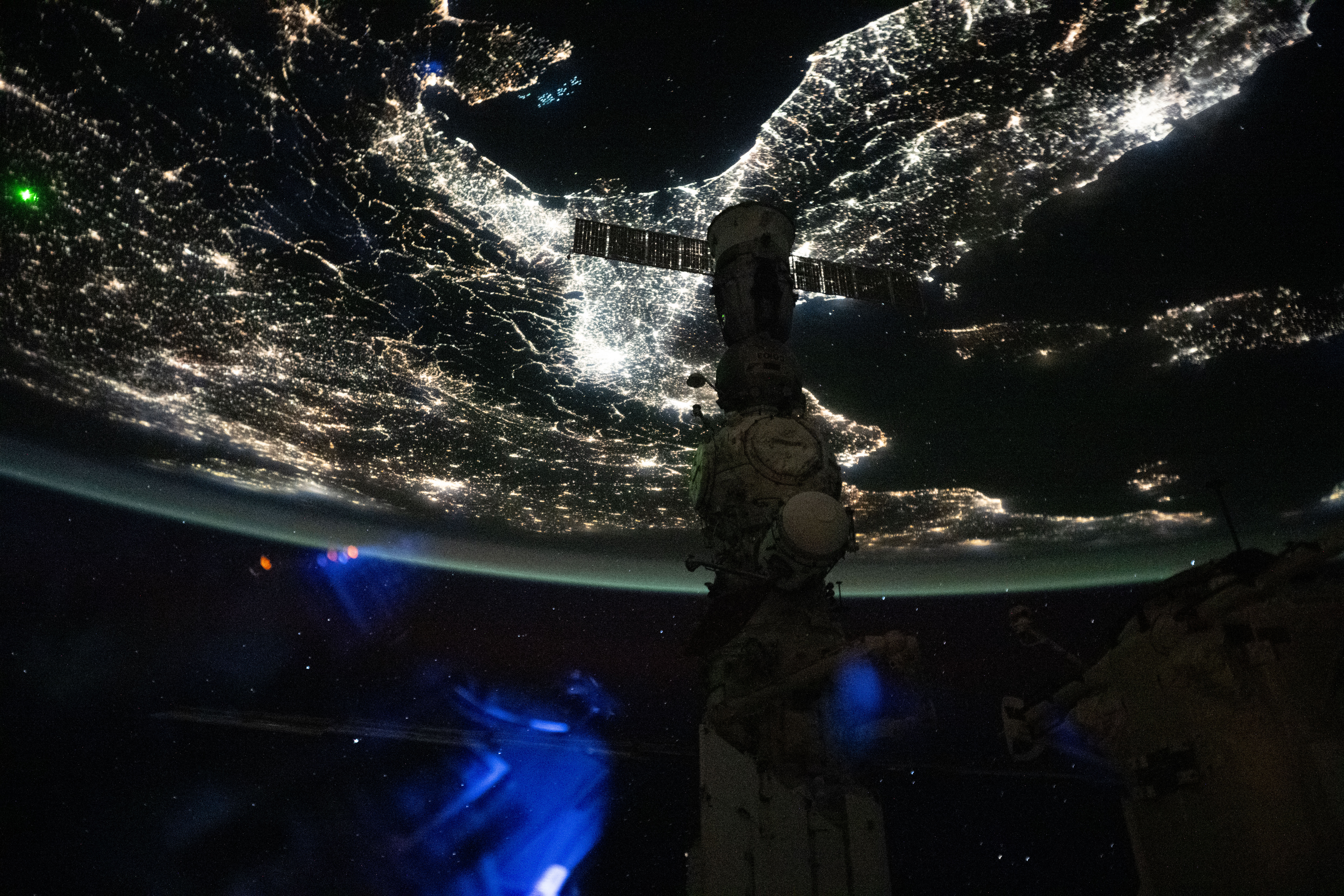 A faint blue-green airglow blankets Earth’s horizon above Italy