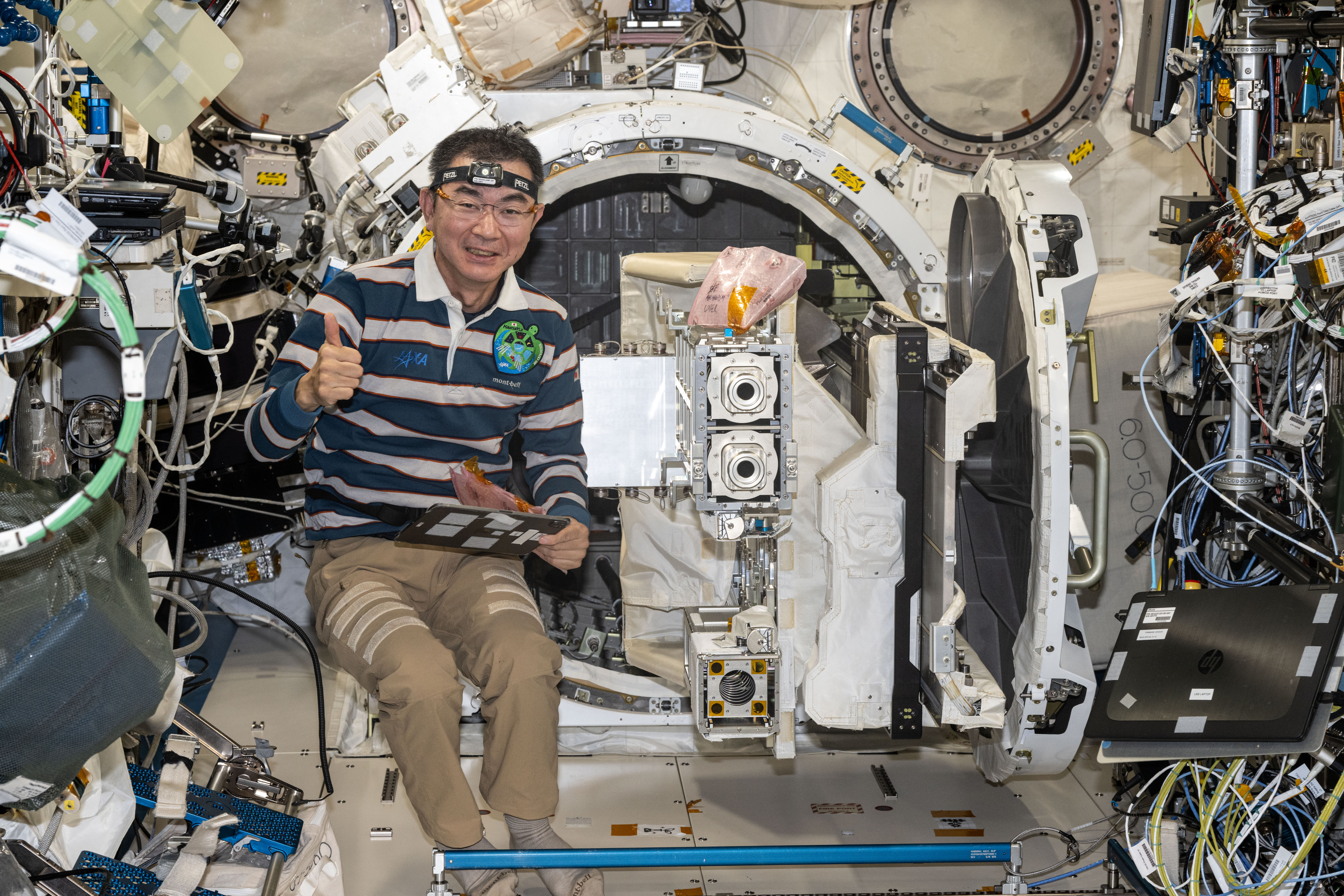 JAXA astronaut Kimiya Yui removes a small satellite orbital deployer from the Kibo airlock