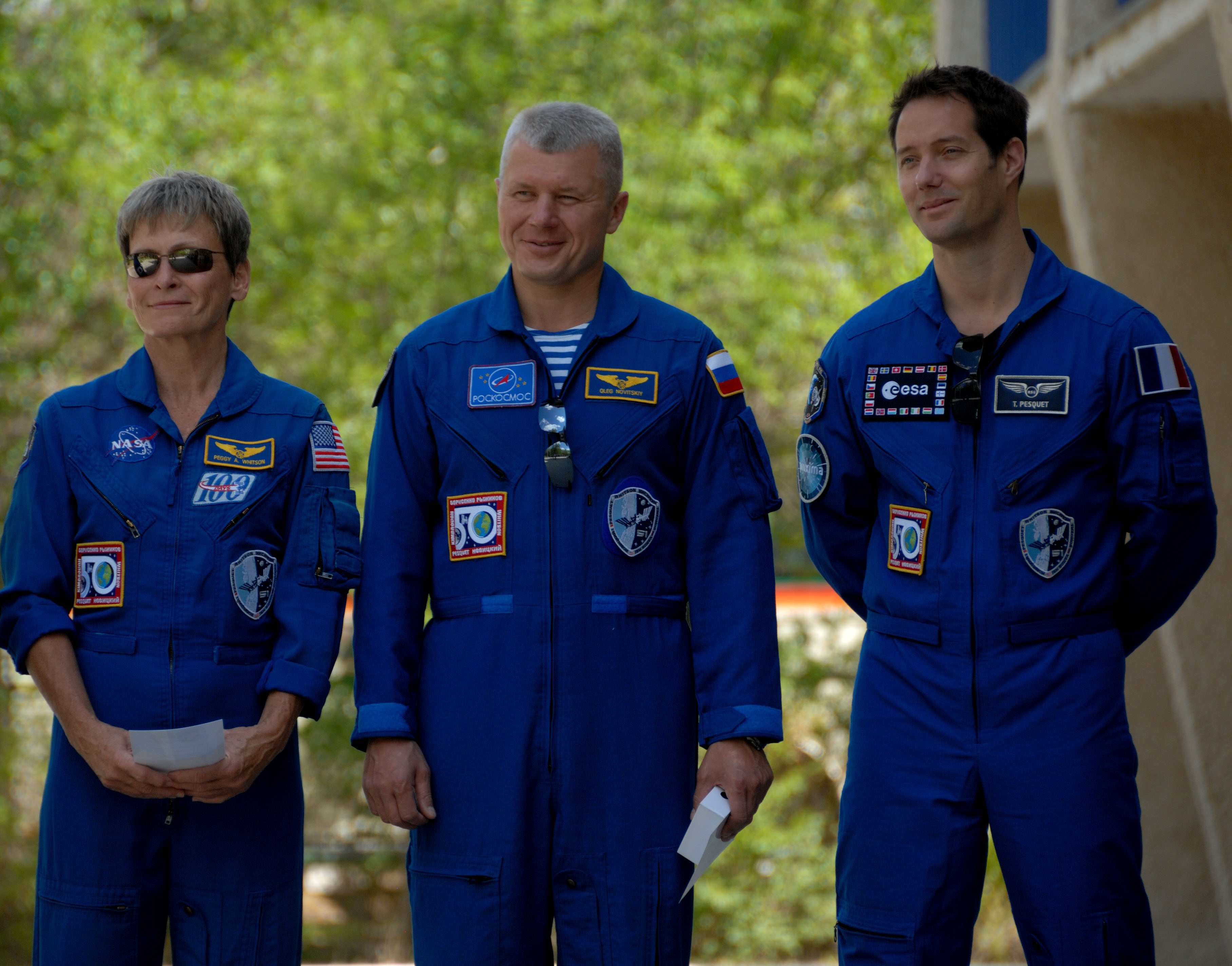 Outside their Cosmonaut Hotel crew quarters in Baikonur, Kazakhstan, Expedition 48-49 backup crewmembers Peggy Whitson of NASA (left), Oleg Novitskiy of Roscosmos (center) and Thomas Pesquet of the European Space Agency (right) listen to remarks June 26 during the traditional raising of the American, Russian, Japanese and Kazakh flags. Prime crewmembers Kate Rubins of NASA, Anatoly Ivanishin of Roscosmos and Takuya Onishi of the Japan Aerospace Exploration Agency will launch on July 7, Baikonur time, on the Soyuz MS-01 spacecraft for a planned four-month mission on the International Space Station...NASA/Alexander Vysotsky.