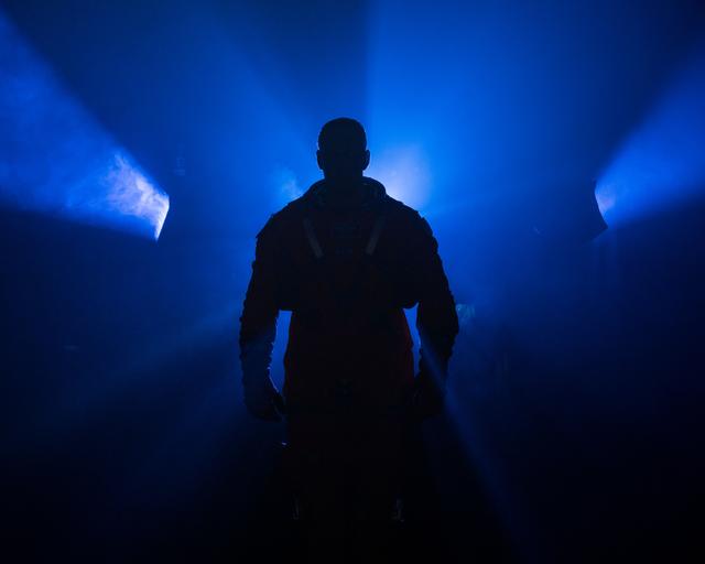 The silhouette of NASA astronaut Bob Hines is pictured with blue lights illuminating the background. 
