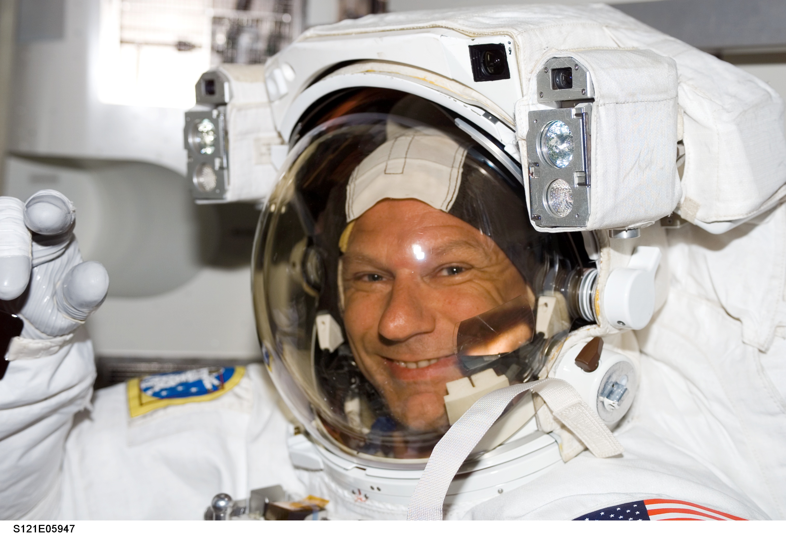 Sellers, waves at camera, as he wears his EMU inside the A/L before EVA1 during STS-121 / Exp. 13 joint OPS