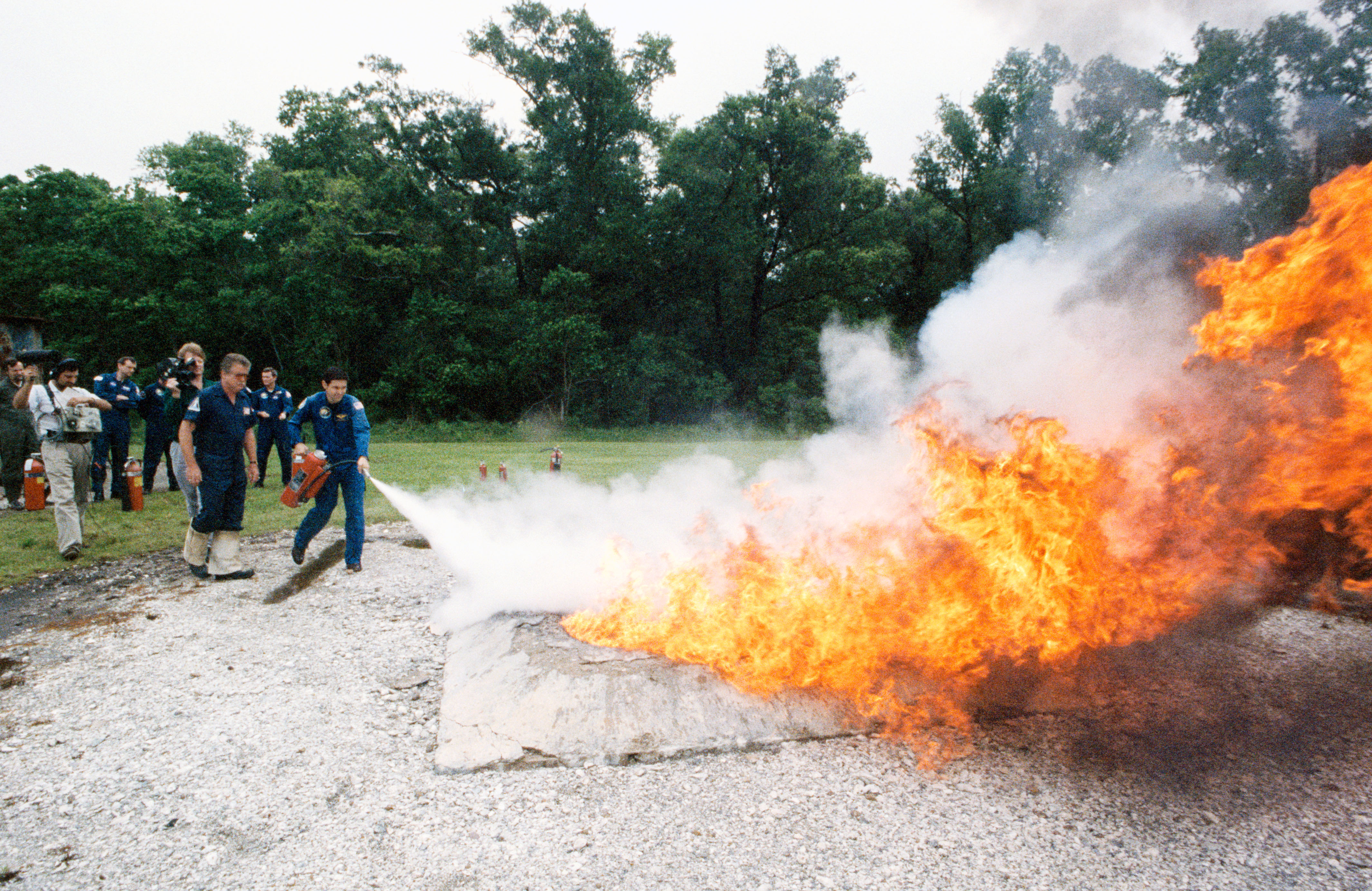 STS-41 crewmembers use fire extinguishers to control blaze at JSC's fire pit