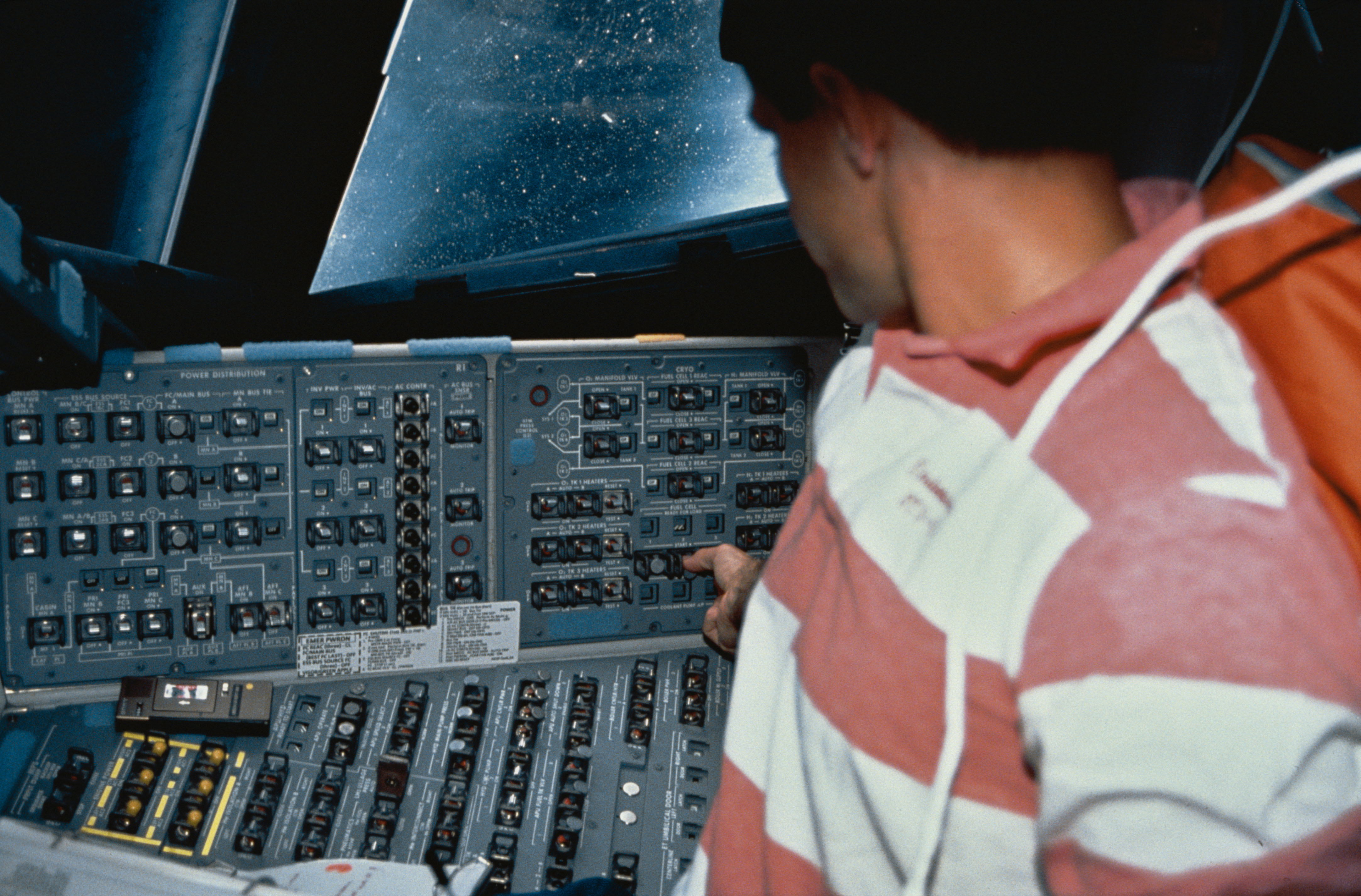 Crewmember in flight deck performing a fuel cell on-orbit shutdown/restart.