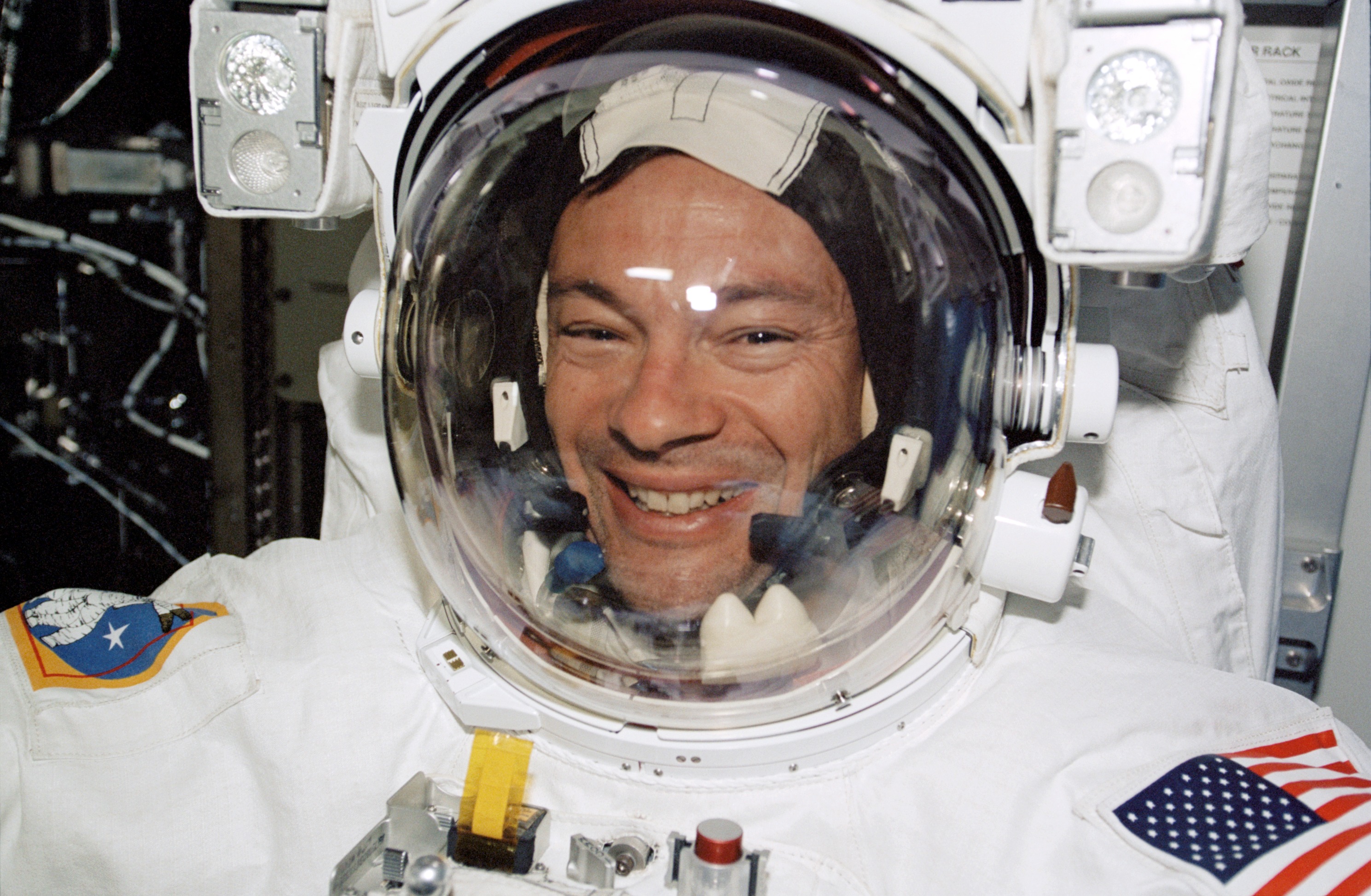 Lopez-Alegria smiles through the helmet of his EMU during preparations for STS-113 EVA 1 in the Quest A/L