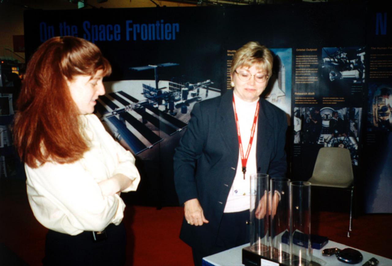 Pat Doty (right) of NASA/Marshall Space Flight Center (MSFC) demonstrates the greater bounce to the ounce of metal made from a supercooled bulk metallic glass alloy that NASA is studying in space expepriments. The metal plates at the bottom of plexiglass tubes are made of three different types of metal. Bulk mettalic glass is more resilient and, as a result, the dropped ball bearing bounces higher. Experiments in space allow scientists to study fundamental properties that carnot be observed on Earth. This demonstration was at the April 2000 conference of the National Council of Teachers of Mathematics (NCTM) in Chicago. Photo credit: NASA/Marshall Space Flight Center (MSFC)