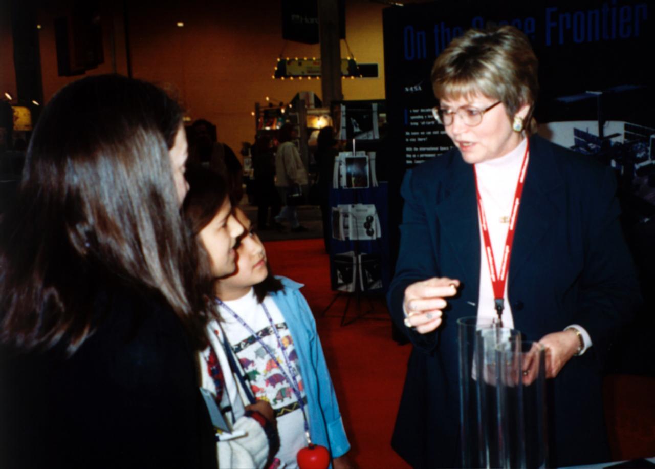 Pat Doty (right) of NASA/Marshall Space Flight Center (MSFC) demonstrates the greater bounce to the ounce of metal made from a supercooled bulk metallic glass alloy that NASA is studying in space experiments. The metal plates at the bottom of the plexiglass tubes are made of three different types of metal. Bulk metallic glass is more resilient and, as a result, the dropped ball bearing bounces higher. Experiments in space allow scientists to study fundamental properties that carnot be observed on Earth. This demonstration was at the April 200 conference of the National Council of Teachers of Mathematics (NCTM) in Chicago. photo credit: NASA/Marshall Space Flight Center (MSFC)