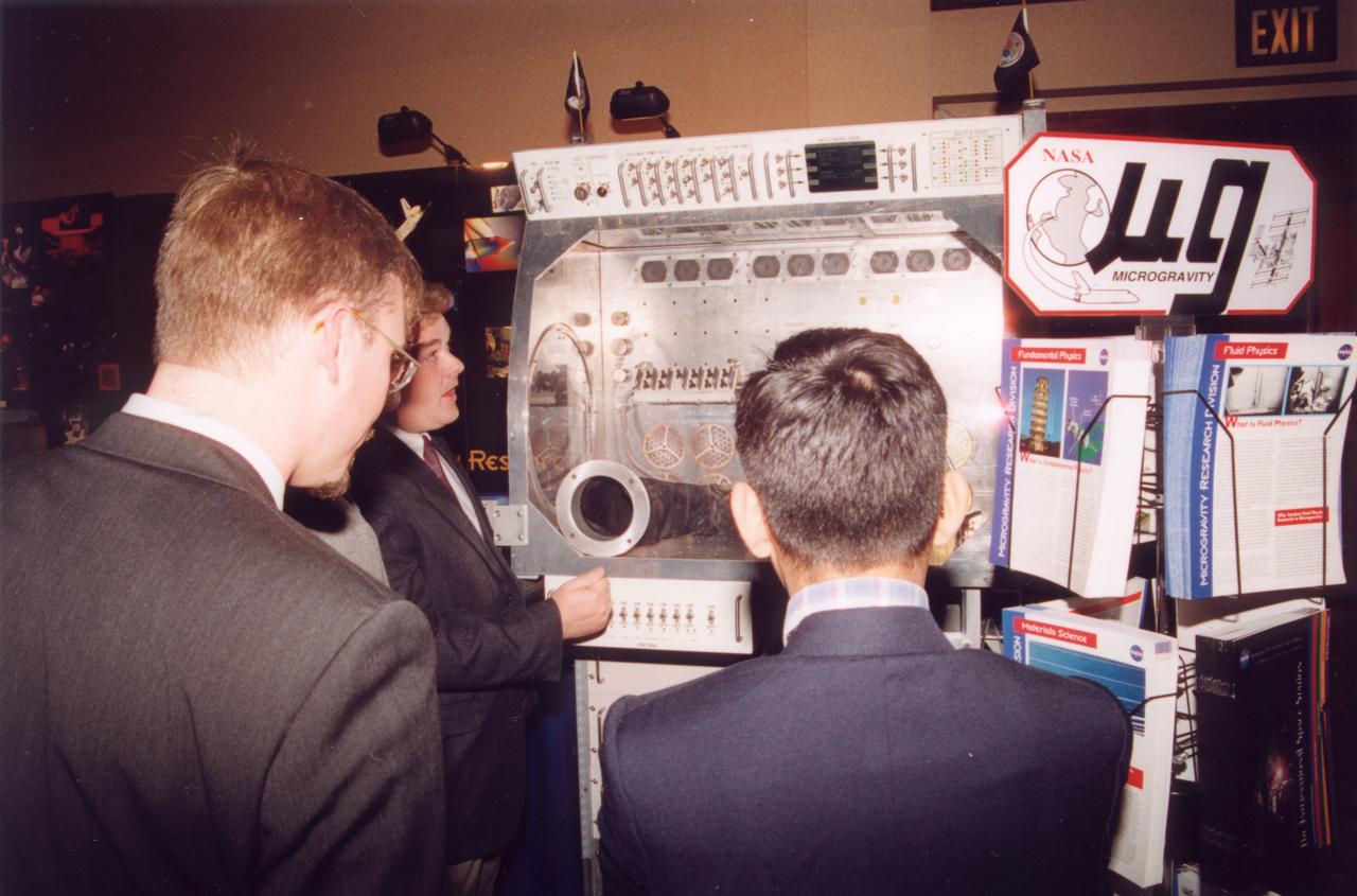 Tim Broach (center) of NASA/Marshall Space Flight Center (MSFC), demonstrates the working volume inside the Microgravity Sciences Glovebox being developed by the European Space Agency (ESA) for use aboard the U.S. Destiny laboratory module on the International Space Station (ISS). This mockup is the same size as the flight hardware. Photo credit: NASA/Marshall Space Flight Center (MSFC)