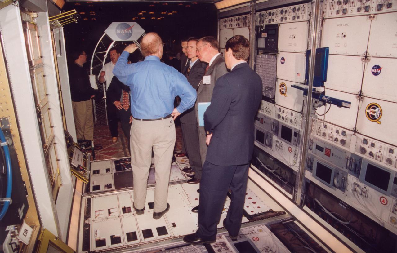 Engineers from NASA's Glenn Research Center demonstrate the access to one of the experiment racks planned for the U.S. Destiny laboratory module on the International Space Station (ISS). This mockup has the full diameter, full corridor width, and half the length of the module. The mockup includes engineering mockups of the Fluids and Combustion Facility being developed by NASA's Glenn Research Center. (The full module will be six racks long; the mockup is three racks long). Listening at center is former astronaut Brewster Shaw (center), now a program official with the Boeing Co., the ISS prime contractor. Photo credit: NASA/Marshall Space Flight Center (MSFC)