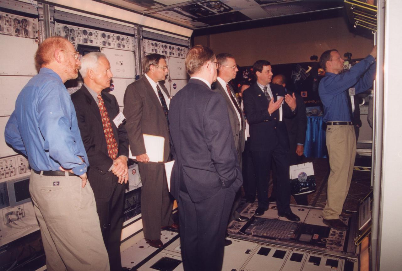 Engineers from NASA's Glenn Research Center demonstrate the access to one of the experiment racks planned for the U.S. Destiny laboratory module on the International Space Station (ISS). This mockup has the full diameter, full corridor width, and half the length of the module. The mockup includes engineering mockups of the Fluids and Combustion Facility being developed by NASA's Glenn Research Center. (The full module will be six racks long; the mockup is three racks long). Listening at left (coat and patterned tie) is John-David Bartoe, ISS research manager at NASA's Johnson Space Center and a payload specialist on Spacelab 2 mission (1985). Photo credit: NASA/Marshall Space Flight Center (MSFC)