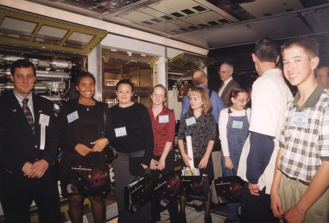 Students from Albuquerque, MN, tour through the mockup of the U.S. Destiny laboratory module that will be attached to the International Space Station (ISS). Behind them are the racks for the Fluids and Combustion Facility being developed by Glenn Research Center. The mockup was on display at the Space Tehnology International Forum in Albuquerque, MN. Photo credit: NASA/Marshall Space Flight Center