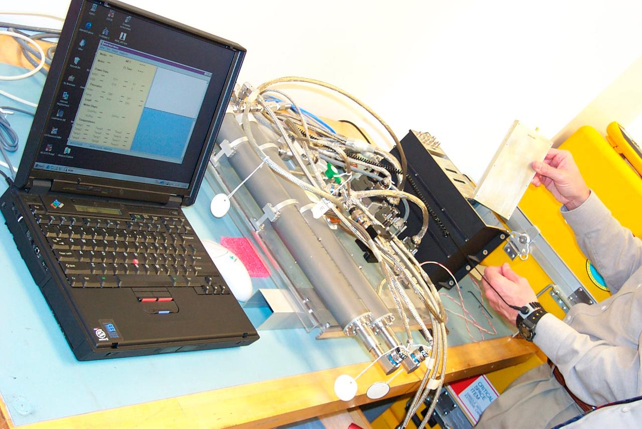 Engineering bench system hardware for the Mechanics of Granular Materials (MGM) experiment is tested on a lab bench at the University of Colorado in Boulder. This is done in a horizontal arrangement to reduce pressure differences so the tests more closely resemble behavior in the microgravity of space. Sand and soil grains have faces that can cause friction as they roll and slide against each other, or even cause sticking and form small voids between grains. This complex behavior can cause soil to behave like a liquid under certain conditions such as earthquakes or when powders are handled in industrial processes. MGM experiments aboard the Space Shuttle use the microgravity of space to simulate this behavior under conditions that carnot be achieved in laboratory tests on Earth. MGM is shedding light on the behavior of fine-grain materials under low effective stresses. Applications include earthquake engineering, granular flow technologies (such as powder feed systems for pharmaceuticals and fertilizers), and terrestrial and planetary geology. Nine MGM specimens have flown on two Space Shuttle flights. Another three are scheduled to fly on STS-107. The principal investigator is Stein Sture of the University of Colorado at Boulder. (Credit: University of Colorado at Boulder).