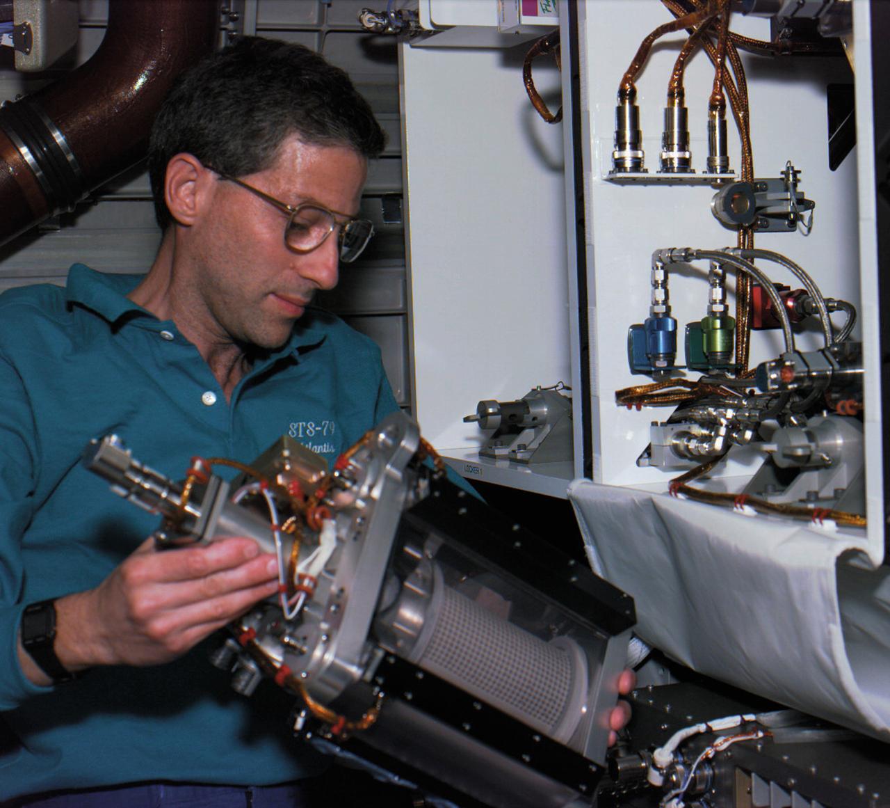 Astronaut Jay Apt installs Mechanics of Granular Materials (MGM0 test cell on STS-79. Sand and soil grains have faces that can cause friction as they roll and slide against each other, or even cause sticking and form small voids between grains. This complex behavior can cause soil to behave like a liquid under certain conditions such as earthquakes or when powders are handled in industrial processes. MGM experiments aboard the Space Shuttle use the microgravity of space to simulate this behavior under conditions that carnot be achieved in laboratory tests on Earth. MGM is shedding light on the behavior of fine-grain materials under low effective stresses. Applications include earthquake engineering, granular flow technologies (such as powder feed systems for pharmaceuticals and fertilizers), and terrestrial and planetary geology. Nine MGM specimens have flown on two Space Shuttle flights. Another three are scheduled to fly on STS-107. The principal investigator is Stein Sture of the University of Colorado at Boulder. (Credit: NASA/John Space Center).