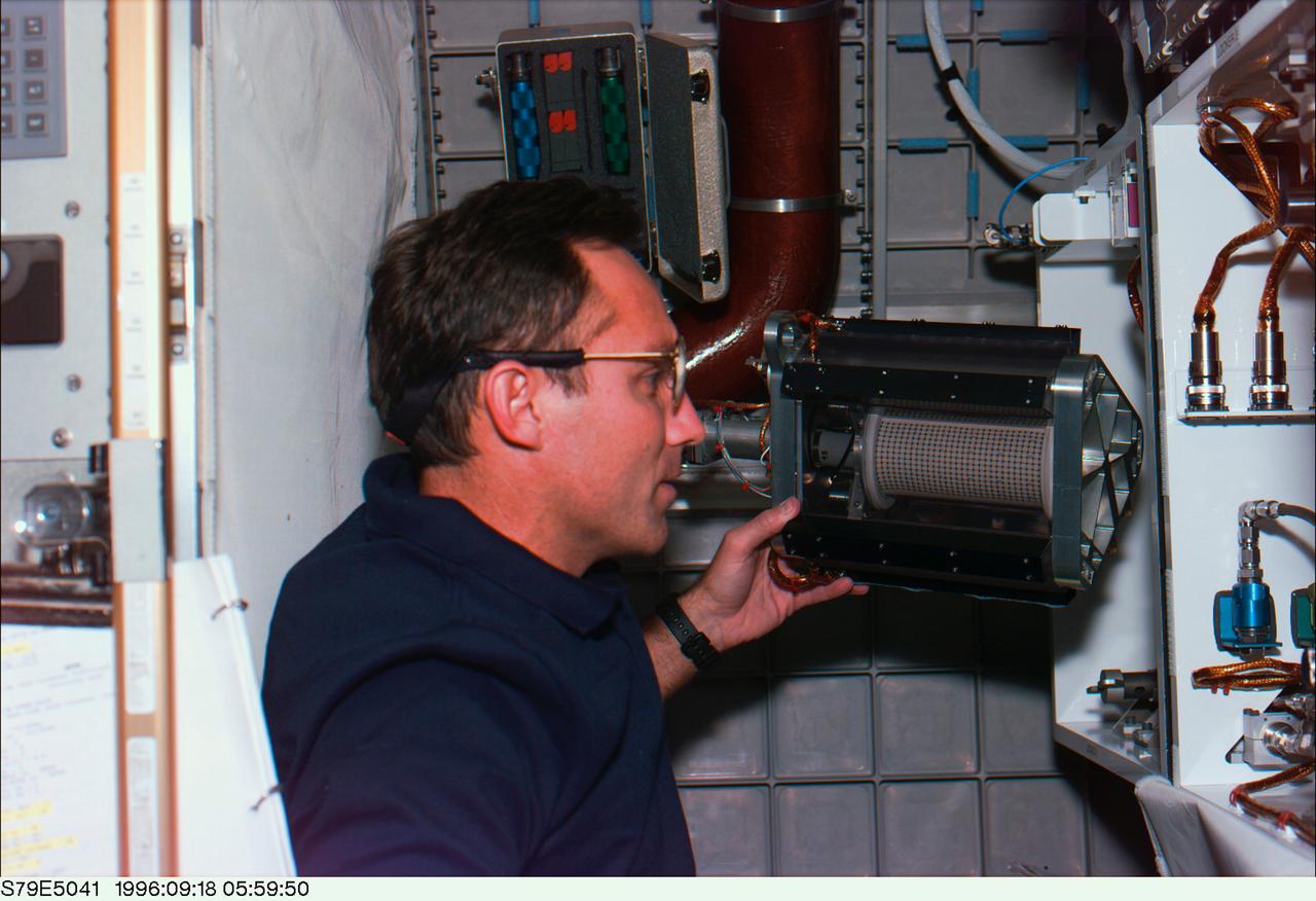 Astronaut Carl Walz installs Mechanics of Granular Materials (MGM) test cell on STS-79. Sand and soil grains have faces that can cause friction as they roll and slide against each other, or even cause sticking and form small voids between grains. This complex behavior can cause soil to behave like a liquid under certain conditions such as earthquakes or when powders are handled in industrial processes. Mechanics of Granular Materials (MGM) experiments aboard the Space Shuttle use the microgravity of space to simulate this behavior under conditons that carnot be achieved in laboratory tests on Earth. MGM is shedding light on the behavior of fine-grain materials under low effective stresses. Applications include earthquake engineering, granular flow technologies (such as powder feed systems for pharmaceuticals and fertilizers), and terrestrial and planetary geology. Nine MGM specimens have flown on two Space Shuttle flights. Another three are scheduled to fly on STS-107. The principal investigator is Stein Sture of the University of Colorado at Boulder. Credit: NASA/John Space Center
