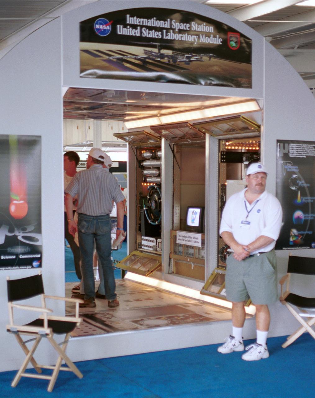 Thomas Turk, an engineer with NASA's Glenn Research Center, waits for more visitors at a mockup of part of Destiny, the U.S. laboratory module that will be attached to the International Space Station (ISS) in Year 2001. Visible behind Turk are engineering models of the three racks that will make up the Fluids and Combustion Facility (FCF) in the module. The mockup is full scale, although Destiny will be twice as long to accomodate six experiment racks along each side. The exhibit was part of the NASA outreach activity at AirVenture 2000 sponsored by the Expeprimental Aircraft Association in Oshkosh, WI.