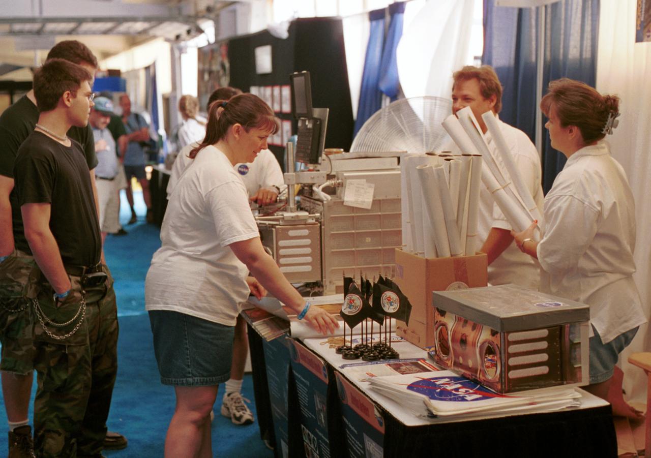 NASA representatives prepare for another day's work answering questions and handing out posters at AirVenture 2000. Part of their demonstrations included a training model of the Middeck Glovebox used aboard the Space Shuttle and Russian Mir Space Station. This and several other devices were used to explain to the public the kinds of research that have been conducted aboard the Space Shuttle and that will continue aboard the International Space Station (ISS). The exhibit was part of the NASA outreach activity at AirVenture 2000 sponsored by the Experimental Aircraft Association in Oshkosh, WI. 