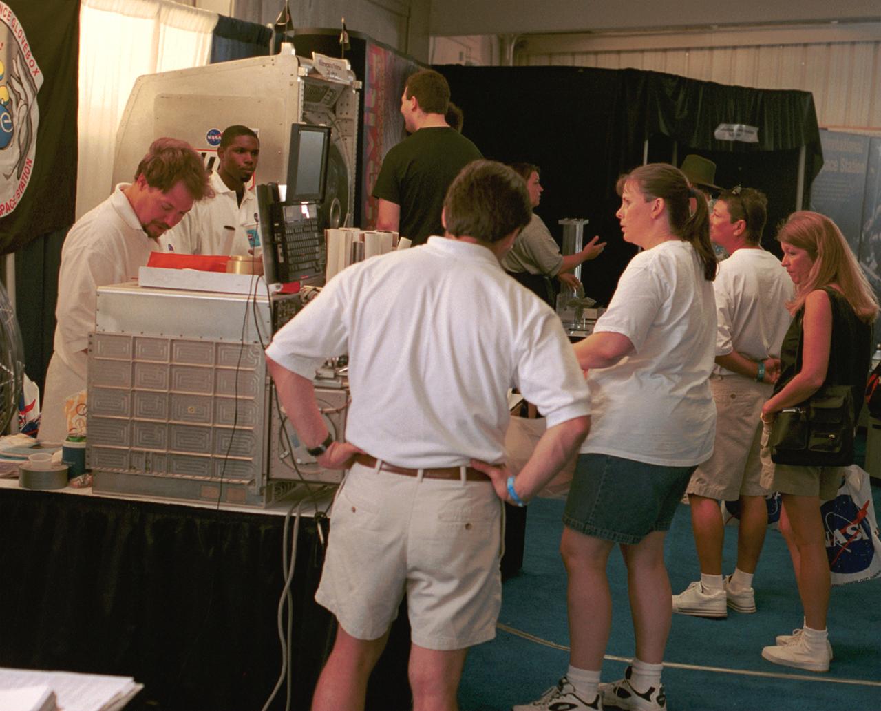 NASA representatives prepare for another day's work answering questions and handing out posters at AirVenture 2000. Part of their demonstrations included a training model of the Middeck Glovebox used aboard the Space Shuttle and Russian Mir Space Station. This and several other devices were used to explain to the public the kinds of research that have been conducted aboard the Space Shuttle and that will continue aboard the International Space Station (ISS). The exhibit was part of the NASA outreach activity at AirVenture 2000 sponsored by the Experimental Aircraft Association in Oshkosh, WI. 