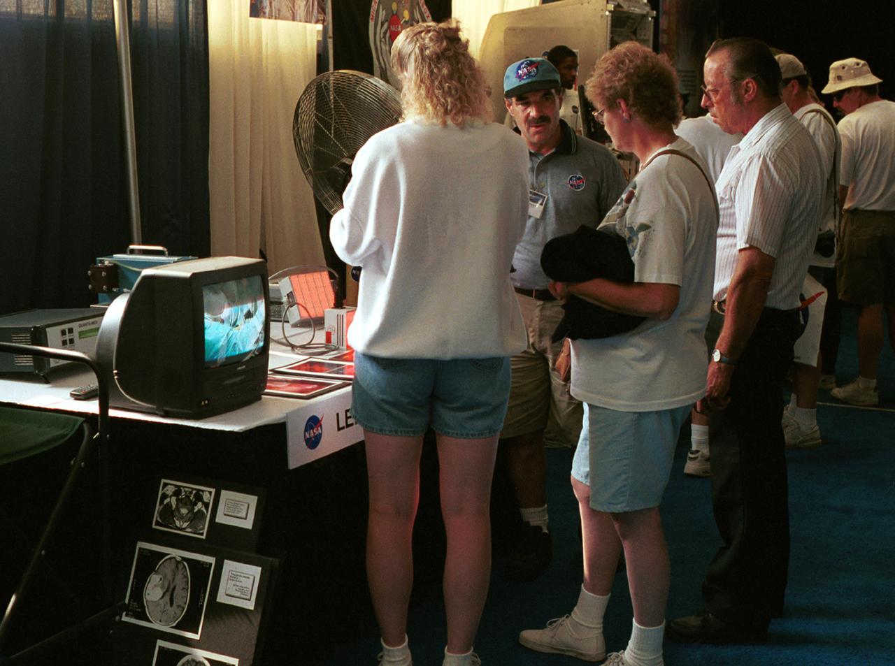 Dr. Harry Whelan, a pediatric Neurologist at the Medical Hospital of Wisconsin in Milwaukee and professor of Neurology at the Medical College of Wisconsin, explains the operation of light-emitting diodes (LEDs) developed for use in space plant growth experiments and now adapted for use in photodynamic therapy, a technique in which light from the LEDs activates light-sensitive, tumor-treating drugs. The technique has been used in at least two surgeries on brain tumors. The LED project was one of several NASA exhibits at AirVenture 2000 sponsored by the Experimental Aircraft Association in Oshkosh, WI. 