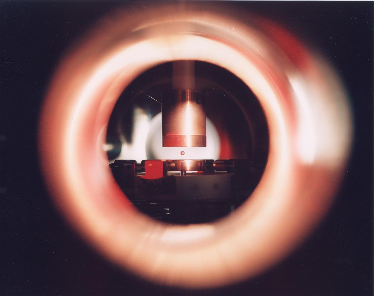 Metal droplet levitated inside the Electrostatic Levitator (ESL). The ESL uses static electricity to suspend an object (about 2-3 mm in diameter) inside a vacuum chamber while a laser heats the sample until it melts. This lets scientists record a wide range of physical properties without the sample contacting the container or any instruments, conditions that would alter the readings. The Electrostatic Levitator is one of several tools used in NASA's microgravity materials science program.