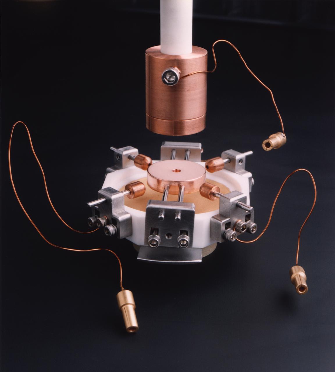 Electrostatic levitation system inside Electrostatic Levitator (ESL) vacuum chamber. The ESL uses static electricity to suspend an object (about 2-3 mm in diameter) inside a vacuum chamber while a laser heats the sample until it melts. This lets scientists record a wide range of physical properties without the sample contacting the container or any instruments, conditions that would alter the readings. The Electrostatic Levitator is one of several tools used in NASA's microgravity materials science program. 