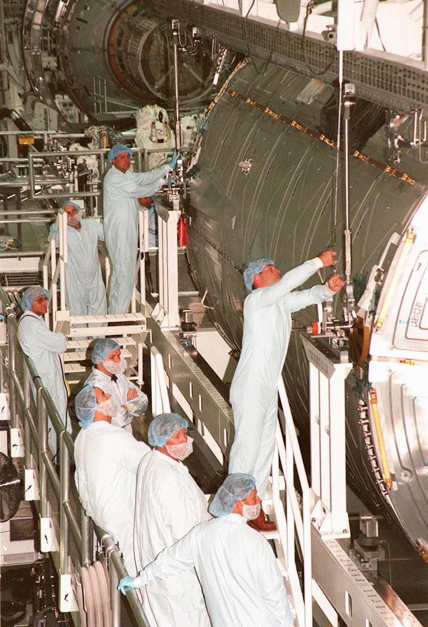 KENNEDY SPACE CENTER, FLA. -- Workers in the Space Station Processing Facility check the connections on the U.S. Lab Destiny to the overhead crane. Destiny rests in the Launch Package Integration Stand (LPIS) where it underwent a weight and center of gravity determination. It is being moved to the payload canister for transfer to Space Shuttle Atlantis. Destiny is the primary payload of STS-98, scheduled for launch no earlier than Jan. 19, 2001. It is one of the key elements of the International Space Station and has five system racks already installed for experiments on the flight