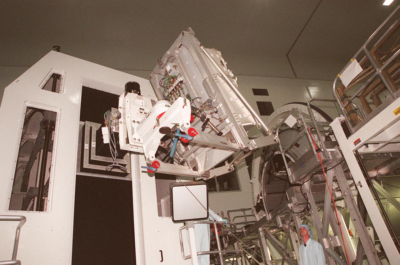 KENNEDY SPACE CENTER, FLA. -- In the Space Station Processing Facility, the Rack Insertion Unit lifts another laboratory rack to the Multi-Purpose Logistics Module Leonardo, in the background. The MPLM is the first of three such pressurized modules that will serve as the International Space Station’s “moving vans,” carrying laboratory racks filled with equipment, experiments and supplies to and from the International Space Station aboard the Space Shuttle. Leonardo will be launched for the first time March 1, 2001, on Shuttle mission STS-102. On that flight, Leonardo will be filled with equipment and supplies to outfit the U.S. laboratory module, being carried to the ISS on the Jan. 19, 2001, launch of STS-98