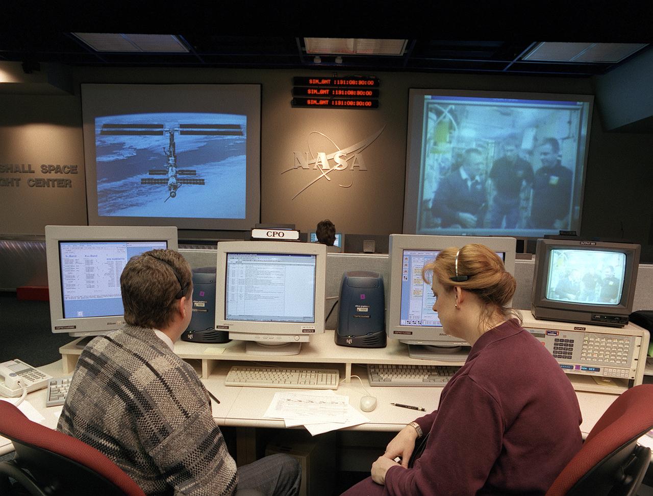 The Payload Operations Center (POC) is the science command post for the International Space Station (ISS). Located at NASA's Marshall Space Flight Center (MSFC) in Huntsville, Alabama, it is the focal point for American and international science activities aboard the ISS. The POC's unique capabilities allow science experts and researchers around the world to perform cutting-edge science in the unique microgravity environment of space. The POC is staffed around the clock by shifts of payload flight controllers. At any given time, 8 to 10 flight controllers are on consoles operating, plarning for, and controlling various systems and payloads. This photograph shows the Command and Payload Multiplexer/Demultiplexer (MDM) Officers (CPO's) at their work stations. The CPO maintains the command link between the Operation Center at MSFC and Mission Control at Johnson Space Center in Houston, Texas, and configures the link to allow the international partners and remote scientists to operate their payloads from their home sites. 