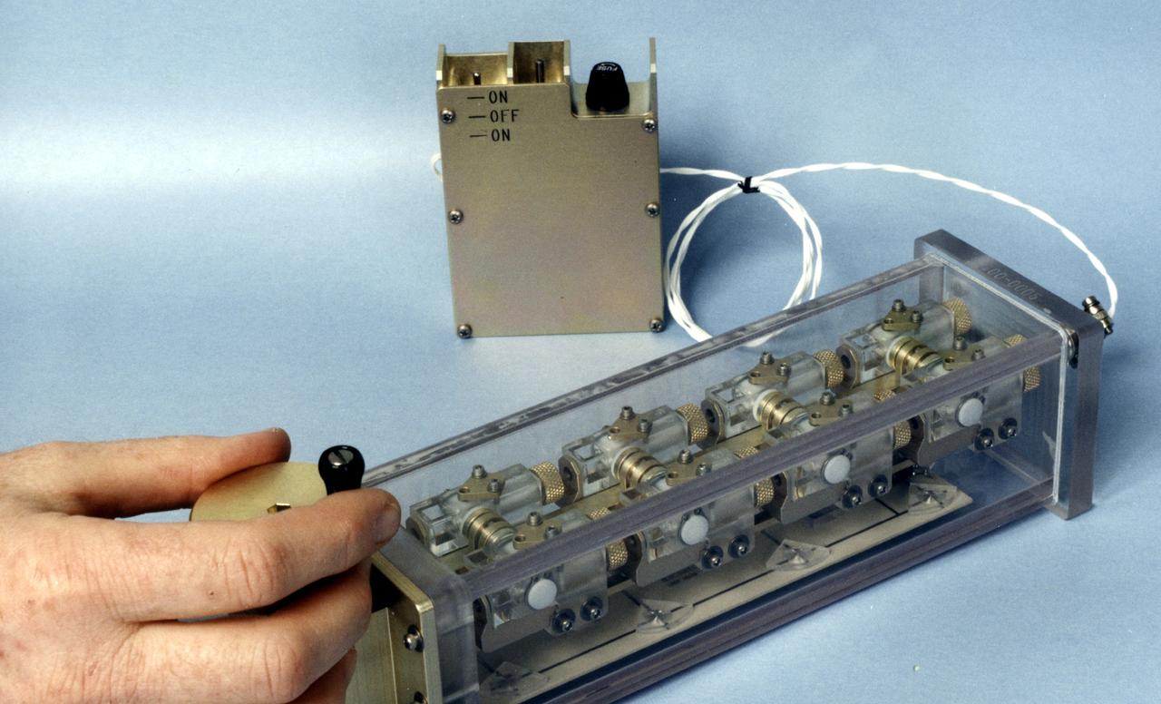 This photo shows the Handheld Diffusion Test Cell (HH-DTC) apparatus flown on the Space Shuttle. Similar cells (inside the plastic box) will be used in the Observable Protein Crystal Growth Apparatus (OPCGA) to be operated aboard the International Space Station (ISS). The principal investigator is Dr. Alex McPherson of the University of California, Irvine. Each individual cell comprises two sample chambers with a rotating center section that isolates the two from each other until the start of the experiment and after it is completed. The cells are made from optical-quality quartz glass to allow photography and interferometric observations. Each cell has a small light-emitting diode and lens to back-light the solution. In protein crystal growth experiments, a precipitating agent such as a salt solution is used to absorb and hold water but repel the protein molecules. This increases the concentration of protein until the molecules nucleate to form crystals. This cell is one of 96 that make up the experiment module portion of the OPCGA.