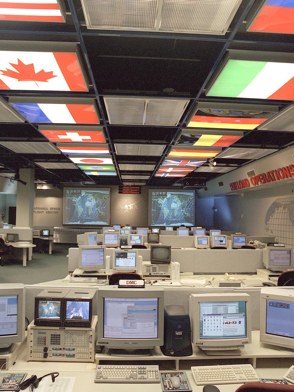 The International Space Station (ISS) Payload Operations Center (POC) at NASA's Marshall Space Flight Center (MSFC) in Huntsville, Alabama, is the world's primary science command post for the (ISS), the most ambitious space research facility in human history. The Payload Operations team is responsible for managing all science research experiments aboard the Station. The center is also home for coordination of the mission-plarning work of variety of international sources, all science payload deliveries and retrieval, and payload training and safety programs for the Station crew and all ground personnel. Within the POC, critical payload information from the ISS is displayed on a dedicated workstation, reading both S-band (low data rate) and Ku-band (high data rate) signals from a variety of experiments and procedures operated by the ISS crew and their colleagues on Earth. The POC is the focal point for incorporating research and experiment requirements from all international partners into an integrated ISS payload mission plan. This photograph is an overall view of the MSFC Payload Operations Center displaying the flags of the countries participating in the ISS. The flags at the left portray The United States, Canada, France, Switzerland, Netherlands, Japan, Brazil, and Sweden. The flags at the right portray The Russian Federation, Italy, Germany, Belgium, Spain, United Kingdom, Denmark, and Norway. 