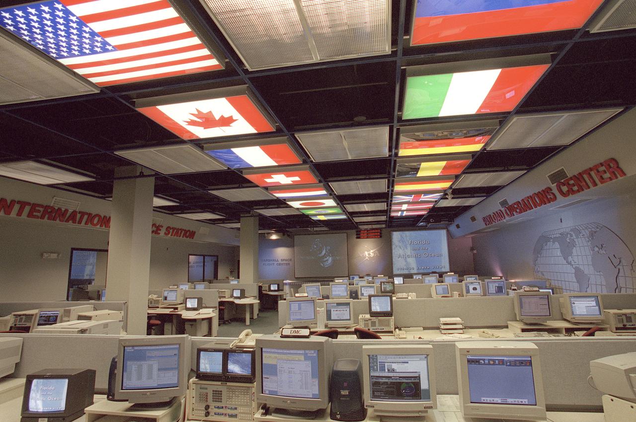 The International Space Station (ISS) Payload Operations Center (POC) at NASA's Marshall Space Flight Center (MSFC) in Huntsville, Alabama, is the world's primary science command post for the International Space Station (ISS), the most ambitious space research facility in human history. The Payload Operations team is responsible for managing all science research experiments aboard the Station. The center is also home for coordination of the mission-plarning work of variety of international sources, all science payload deliveries and retrieval, and payload training and safety programs for the Station crew and all ground personnel. Within the POC, critical payload information from the ISS is displayed on a dedicated workstation, reading both S-band (low data rate) and Ku-band (high data rate) signals from a variety of experiments and procedures operated by the ISS crew and their colleagues on Earth. The POC is the focal point for incorporating research and experiment requirements from all international partners into an integrated ISS payload mission plan. This photograph is an overall view of the MSFC Payload Operations Center displaying the flags of the countries participating the ISS. The flags at the left portray The United States, Canada, France, Switzerland, Netherlands, Japan, Brazil, and Sweden. The flags at the right portray The Russian Federation, Italy, Germany, Belgium, Spain, United Kingdom, Denmark, and Norway. 