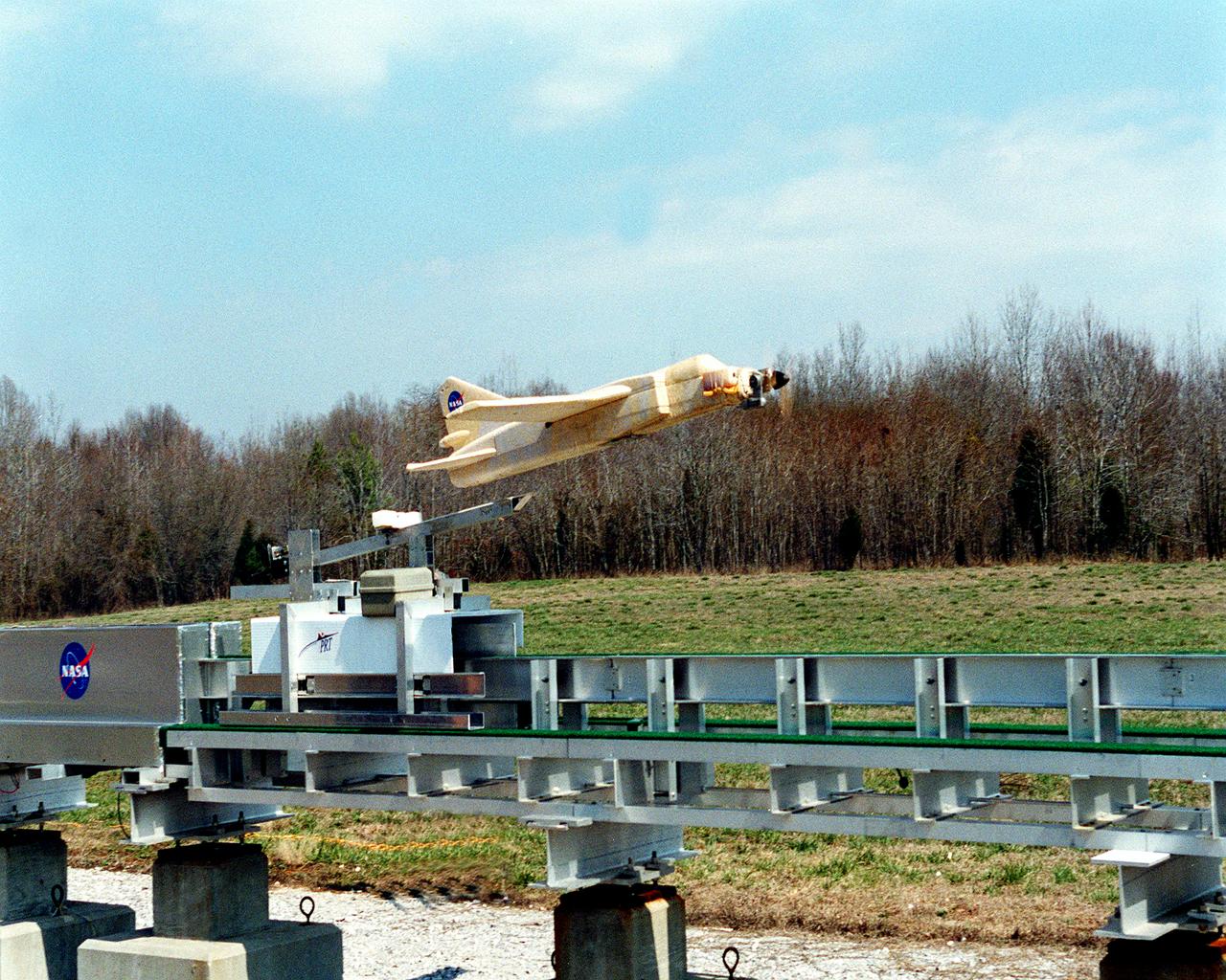 This image shows a 1/9 subscale model vehicle clearing the Magnetic Launch Assist System, formerly referred to as the Magnetic Levitation (MagLev), test track during a demonstration test conducted at the Marshall Space Flight Center (MSFC). Engineers at MSFC have developed and tested Magnetic Launch Assist technologies. To launch spacecraft into orbit, a Magnetic Launch Assist System would use magnetic fields to levitate and accelerate a vehicle along a track at very high speeds. Similar to high-speed trains and roller coasters that use high-strength magnets to lift and propel a vehicle a couple of inches above a guideway, a launch-assist system would electromagnetically drive a space vehicle along the track. A full-scale, operational track would be about 1.5-miles long and capable of accelerating a vehicle to 600 mph in 9.5 seconds.  This track is an advanced linear induction motor. Induction motors are common in fans, power drills, and sewing machines. Instead of spinning in a circular motion to turn a shaft or gears, a linear induction motor produces thrust in a straight line. Mounted on concrete pedestals, the track is 100-feet long, about 2-feet wide and about 1.5-feet high. The major advantages of launch assist for NASA launch vehicles is that it reduces the weight of the take-off, the landing gear, the wing size, and less propellant resulting in significant cost savings. The US Navy and the British MOD (Ministry of Defense) are planning to use magnetic launch assist for their next generation aircraft carriers as the aircraft launch system.  The US Army is considering using this technology for launching target drones for anti-aircraft training. 
