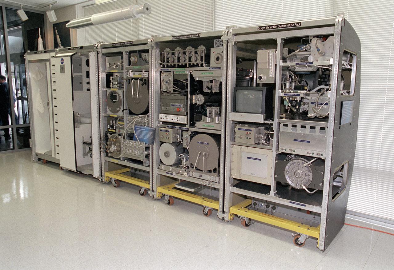 The Environmental Control and Life Support System (ECLSS) Group of the Flight Projects Directorate at the Marshall Space Flight Center in Huntsville, Alabama, is responsible for designing and building the life support systems that will provide the crew of the International Space Station (ISS) a comfortable environment in which to live and work. This photograph shows the mockup of the the ECLSS to be installed in the Node 3 module of the ISS. From left to right, shower rack, waste management rack, Water Recovery System (WRS) Rack #2, WRS Rack #1, and Oxygen Generation System (OGS) rack are shown. The WRS provides clean water through the reclamation of wastewaters and is comprised of a Urine Processor Assembly (UPA) and a Water Processor Assembly (WPA). The UPA accepts and processes pretreated crewmember urine to allow it to be processed along with other wastewaters in the WPA. The WPA removes free gas, organic, and nonorganic constituents before the water goes through a series of multifiltration beds for further purification. The OGS produces oxygen for breathing air for the crew and laboratory animals, as well as for replacing oxygen loss. The OGS is comprised of a cell stack, which electrolyzes (breaks apart the hydrogen and oxygen molecules) some of the clean water provided by the WRS, and the separators that remove the gases from the water after electrolysis. 
