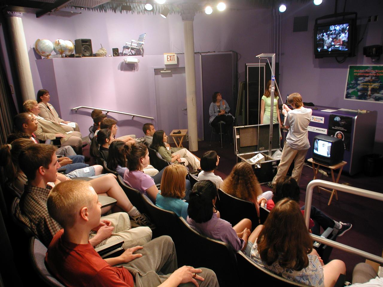 John Henson (grade 12) and Suzi Bryce (grade 10) from DuPont Manual High School in Louisville, Kentucky, conduct a drop with NASA's Microgravity Demonstrator. A camera and a TV/VCR unit let students play back recordings of how different physical devices behave differently during freefall as compared to 1-g. The activity was part of the education outreach segment of the Pan-Pacific Basin Workshop on Microgravity Sciences held in Pasadena, California. The event originated at the California Science Center in Los Angeles. The DuPont Manual students patched in to the event through the distance learning lab at the Louisville Science Center. This image is from a digital still camera; higher resolution is not available.