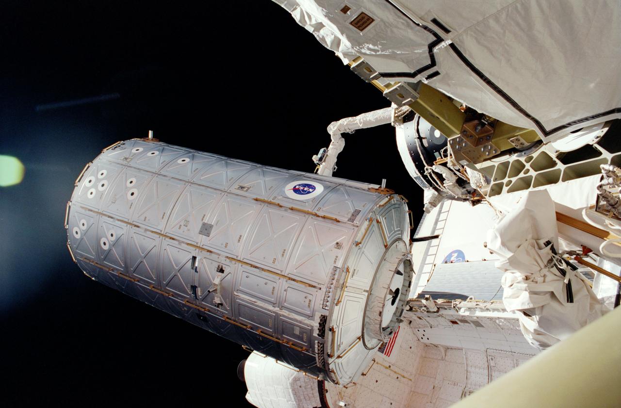 In the grasp of the Shuttle's Remote Manipulator System (RMS) robot arm, the U.S. Laboratory, Destiny, is moved from its stowage position in the cargo bay of the Space Shuttle Atlantis. This photograph was taken by astronaut Thomas D. Jones during his Extravehicular Activity (EVA). The American-made Destiny module is the cornerstone for space-based research aboard the orbiting platform and the centerpiece of the International Space Station (ISS), where unprecedented science experiments will be performed in the near-zero gravity of space. Destiny will also serve as the command and control center for the ISS. The aluminum module is 8.5- meters (28-feet) long and 4.3-meters (14-feet) in diameter. The laboratory consists of three cylindrical sections and two endcones with hatches that will be mated to other station components. A 50.9-centimeter (20-inch-) diameter window is located on one side of the center module segment. This pressurized module is designed to accommodate pressurized payloads. It has a capacity of 24 rack locations. Payload racks will occupy 15 locations especially designed to support experiments. The Destiny module was built by the Boeing Company under the direction of the Marshall Space Flight Center. 