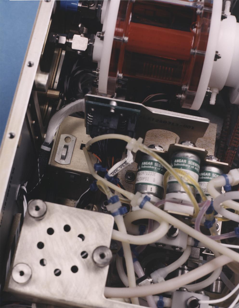 Close-up view of the interior of a NASA Bioreactor shows the plastic plumbing and valves (cylinders at right center) to control fluid flow. The rotating wall vessel is at top center. The NASA Bioreactor provides a low turbulence culture environment which promotes the formation of large, three-dimensional cell clusters. The Bioreactor is rotated to provide gentle mixing of fresh and spent nutrient without inducing shear forces that would damage the cells. Due to their high level of cellular organization and specialization, samples constructed in the bioreactor more closely resemble the original tumor or tissue found in the body. The work is sponsored by NASA's Office of Biological and Physical Research. The bioreactor is managed by the Biotechnology Cell Science Program at NASA's Johnson Space Center (JSC). NASA-sponsored bioreactor research has been instrumental in helping scientists to better understand normal and cancerous tissue development. In cooperation with the medical community, the bioreactor design is being used to prepare better models of human colon, prostate, breast and ovarian tumors. Cartilage, bone marrow, heart muscle, skeletal muscle, pancreatic islet cells, liver and kidney are just a few of the normal tissues being cultured in rotating bioreactors by investigators.