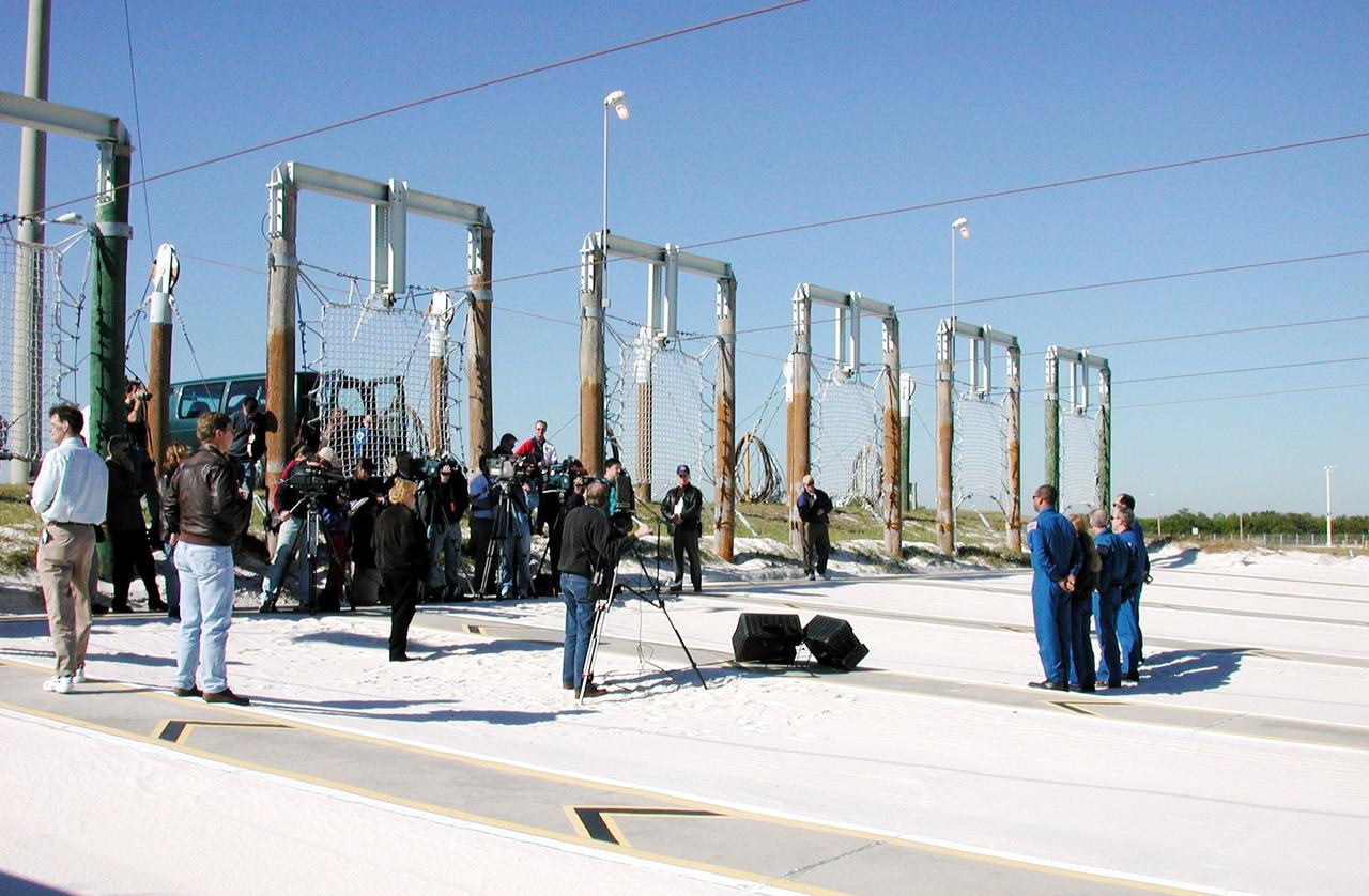 KENNEDY SPACE CENTER, Fla. -- The STS-98 crew (right) gathers at Launch Pad 39A for a media briefing before continuing their emergency egress training. Facing an audience (left) of photographers, videographers and writers, along with KSC media escorts, are (left to right) Mission Specialist Robert Curbeam and Marsha Ivins, Commander Ken Cockrell, Mission Specialist Thomas Jones and Pilot Mark Polansky. They are standing in the landing zone for the slidewire baskets that provide an escape route for personnel aboard the Space Shuttle and orbiter access arm until 30 seconds before launch. The crew is at KSC to take part in Terminal Countdown Demonstration Test activities, which also include a simulated launch countdown. STS-98 is the seventh construction flight to the International Space Station, carrying as payload the U.S. Lab Destiny, a key element in the construction of the ISS. Launch of STS-98 is scheduled for Jan. 19 at 2:11 a.m. EST