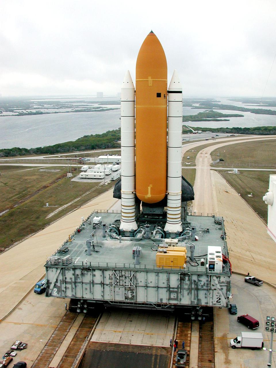 KENNEDY SPACE CENTER, FLA. -- Perched atop its Mobile Launcher Platform, Space Shuttle Atlantis moves back to the Vehicle Assembly Building, via the crawler-transporter underneath, along the crawlerway. The water in the background is part of the Banana River. Atlantis’ return to the VAB was determined by Shuttle managers so that inspections, continuity checks and X-ray analysis can be conducted on the 36 solid rocket booster cables located inside each booster’s system tunnel. An extensive evaluation of NASA’s SRB cable inventory revealed conductor damage in four (of about 200) cables on the shelf. The launch has been rescheduled no earlier than Feb. 6