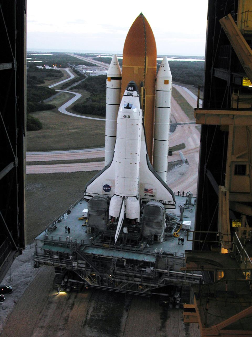 KENNEDY SPACE CENTER, Fla. -- Reflecting light from framework inside the Vehicle Assembly Building, Space Shuttle Atlantis begins rolling out of the VAB to Launch Pad 39A after tests were completed on the solid rocket booster cables. A prior extensive evaluation of NASA’s SRB cable inventory on the shelf revealed conductor damage in four (of about 200) cables. Shuttle managers decided to prove the integrity of the system tunnel cables already on Atlantis, causing return of the Shuttle to the VAB a week ago. Launch of Atlantis on STS-98 has been rescheduled to Feb. 7 at 6:11 p.m. EST