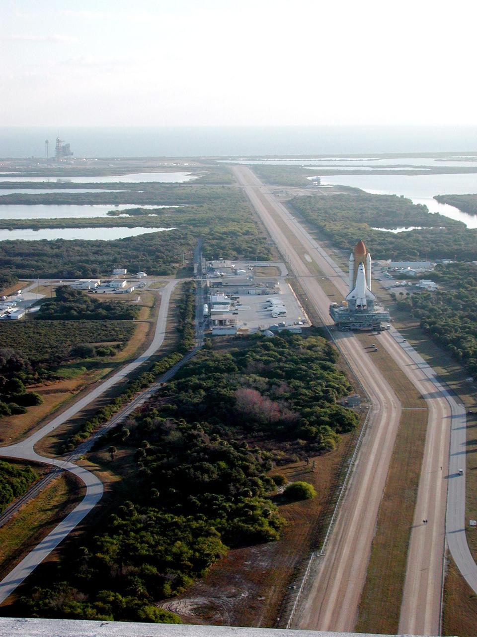 KENNEDY SPACE CENTER, Fla. -- Photographed from the top of the Vehicle Assembly Building, Space Shuttle Atlantis creeps along the crawlerway for the trek to Launch Pad 39A (upper left). In the background is the Atlantic Ocean. The Shuttle has been in the VAB undergoing tests on the solid rocket booster cables. A prior extensive evaluation of NASA’s SRB cable inventory on the shelf revealed conductor damage in four (of about 200) cables. Shuttle managers decided to prove the integrity of the system tunnel cables already on Atlantis, causing return of the Shuttle to the VAB a week ago. Launch of Atlantis on STS-98 has been rescheduled to Feb. 7 at 6:11 p.m. EST