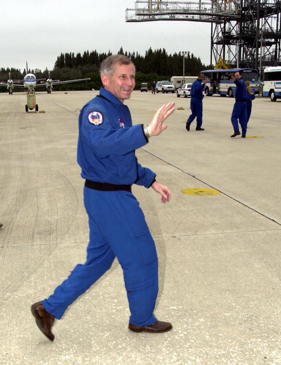 KENNEDY SPACE CENTER, FLA. -- STS-98 Mission Commander Kenneth Cockrell waves to his family at the Shuttle Landing Facility after the crew's arrival Sunday to complete preparations for launch.; In the background, Mission Specialist Robert Curbeam (left) and Pilot Mark Polansky are also caught waving.; The crew is preparing to board a bus for transport to the Operations and Checkout Building where the crew quarters at KSC is located. Crew members Thomas Jones and Marsha Ivins, both mission specialists, are not in plain view.; STS-98 is the seventh construction flight to the International Space Station, carrying as payload the U.S. Lab Destiny, a key element in the construction of the ISS. Launch of STS-98 is scheduled for Feb. 7 at 6:11 p.m. EST