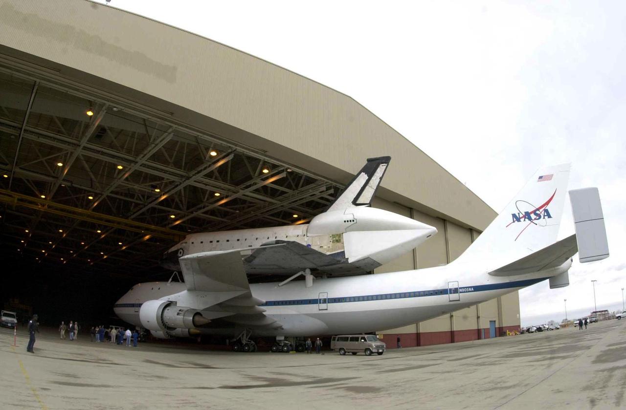 <i>[Photo courtesy of Boeing photographer Bob Williams.]<_i> The orbiter Columbia, atop a modified Boeing 747, rolls under protective cover at Palmdale, Calif. Columbia has been undergoing modifications and upgrades at Boeing’s Orbiter Assembly Facility in Palmdale and is ready to return to Kennedy Space Center. Ferry preparations and the flight plan are contingent upon weather conditions in California and enroute to Florida.