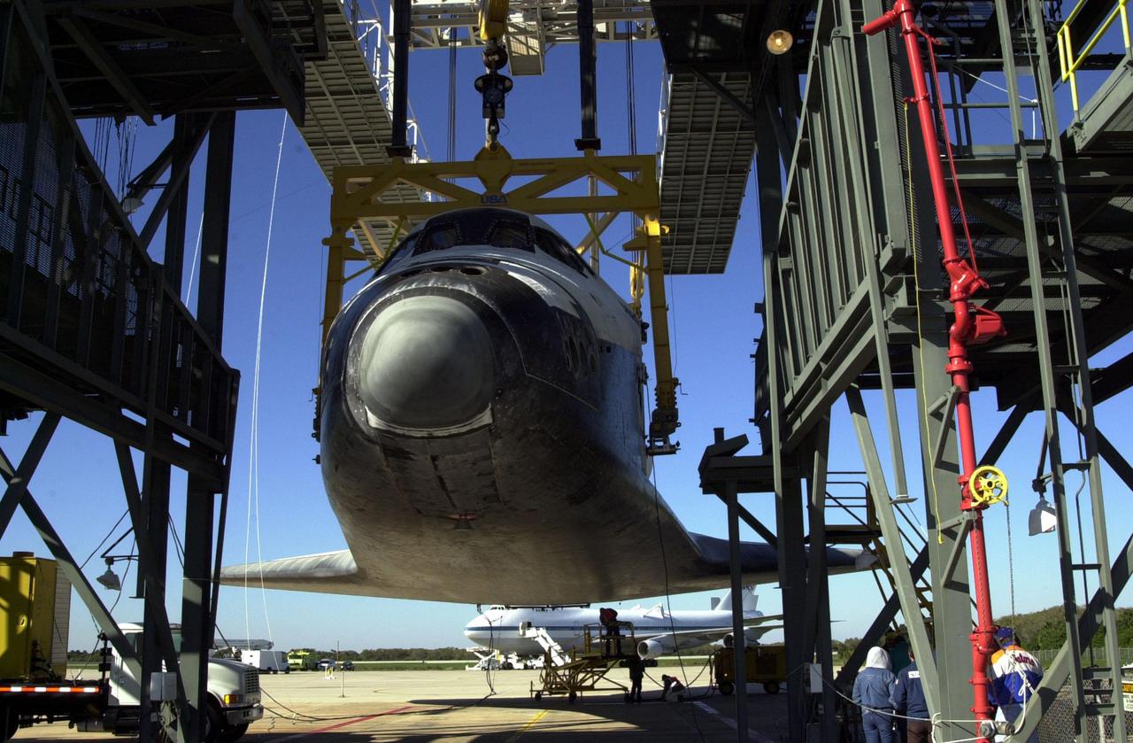 KENNEDY SPACE CENTER, FLA. -- Orbiter Atlantis is suspended by an overhead crane in the mate_demate device at KSC’s Shuttle Landing Facility. It was removed from the back of the Shuttle Carrier Aircraft in the background. Atlantis just returned from California atop the SCA after its Feb. 19 landing at Edwards Air Force Base concluding mission STS-98. The ferry flight began March 1; unfavorable weather conditions kept it on the ground at Altus AFB, Okla., until it could return to Florida. Atlantis will be transported to the Orbiter Processing Facility to prepare it for mission STS-104, the 10th construction flight to the International Space Station, scheduled to launch June 8